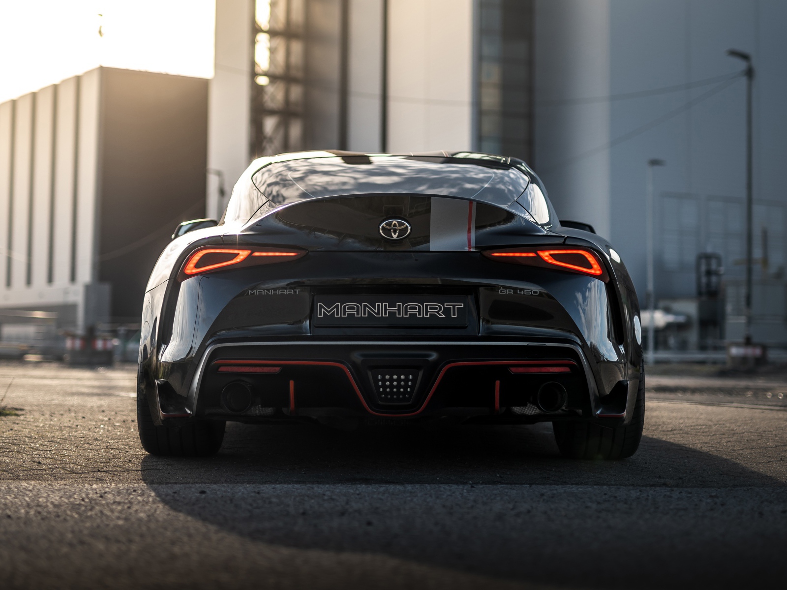 Черный автомобиль Manhart Supra GR 450 2020 года у домов