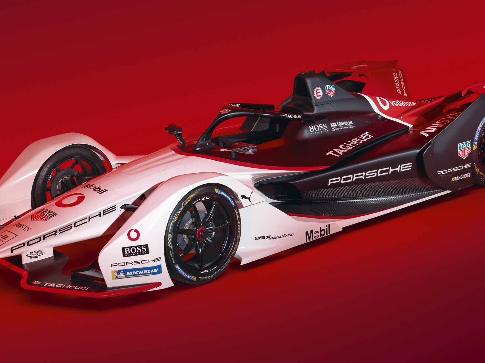Гоночный автомобиль Porsche 99X Electric 2019 года на красном фоне
