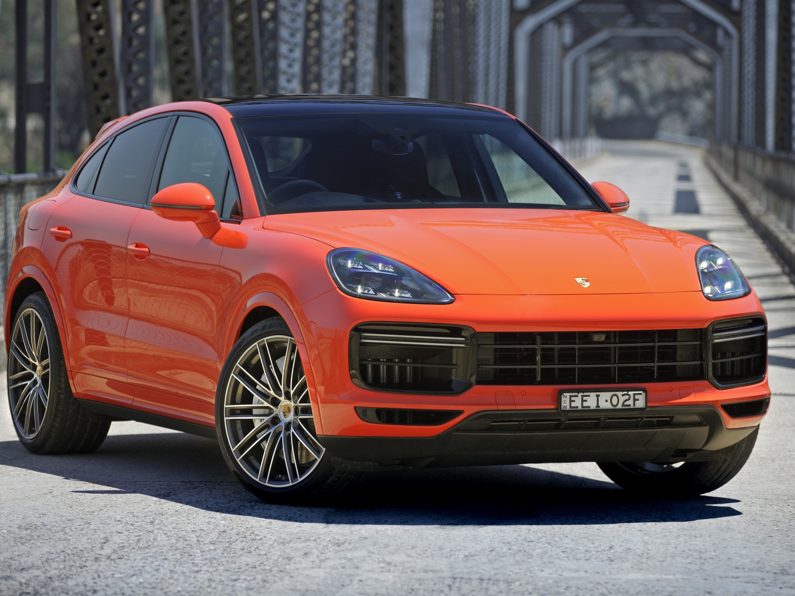 Оранжевый внедорожник Porsche Cayenne Turbo Coupe 2019 года на мосту