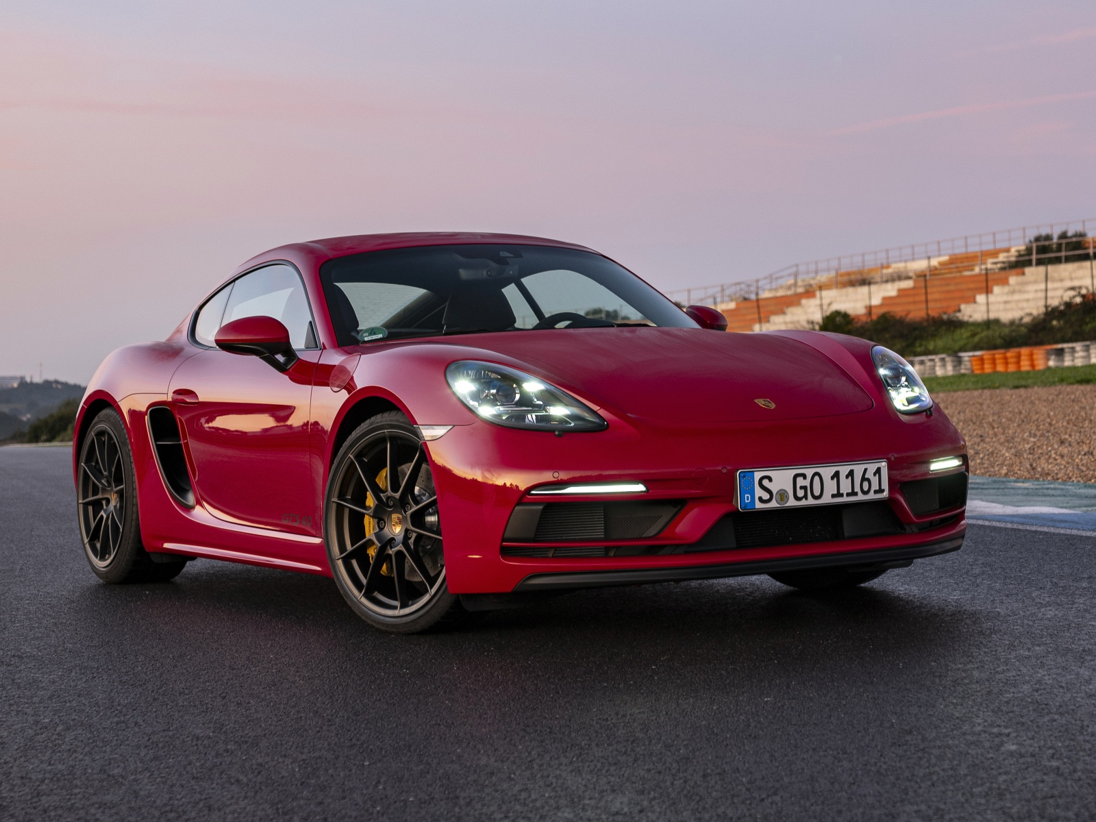 Красный автомобиль Porsche 718 Cayman GTS 4,  2020  года на стадионе