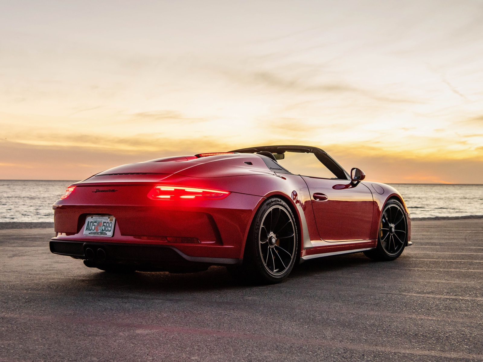 Красный автомобиль Porsche 911 Speedster, 2019 года у моря на закате