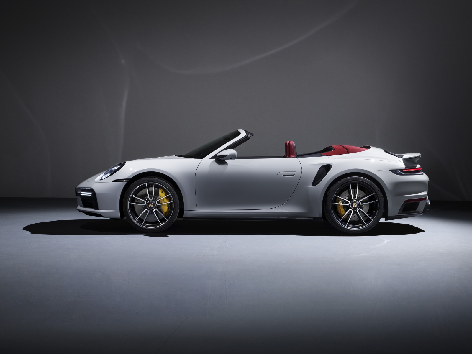 Белый автомобиль Porsche 911 Turbo S Cabriolet 2020 года на сером фоне