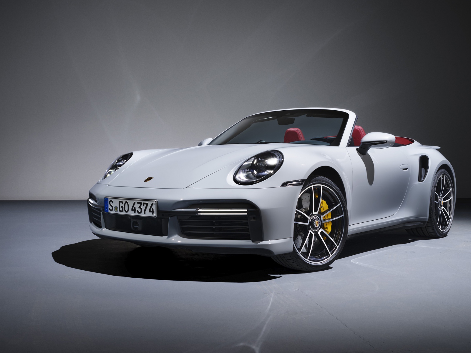 Белый кабриолет Porsche 911 Turbo S 2020 года на сером фоне