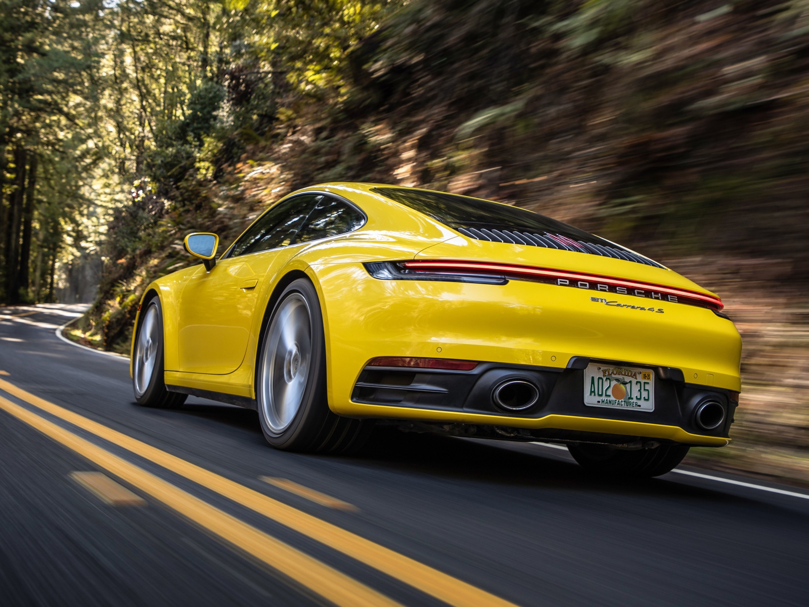 Желтый автомобиль  Porsche 911 Carrera 4S, 2020 года на трассе 
