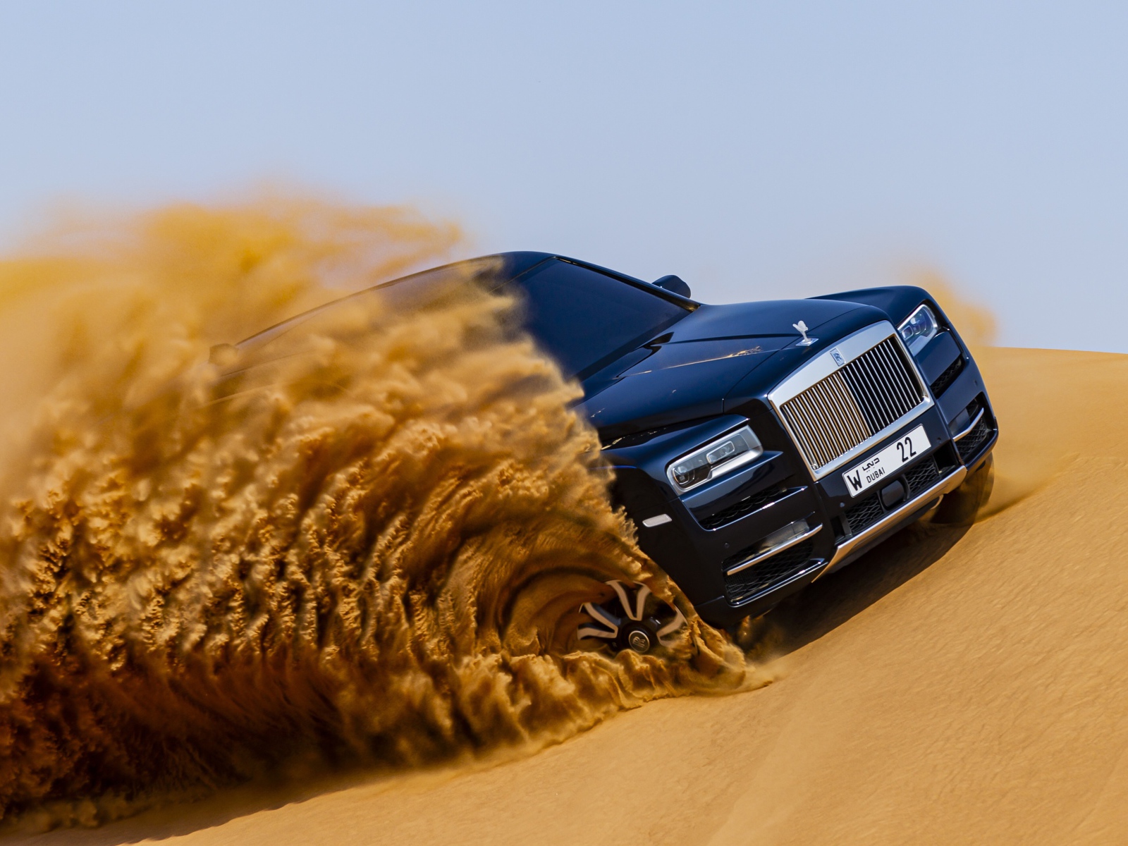 Черный Rolls-Royce Cullinan дрифтует по песку 