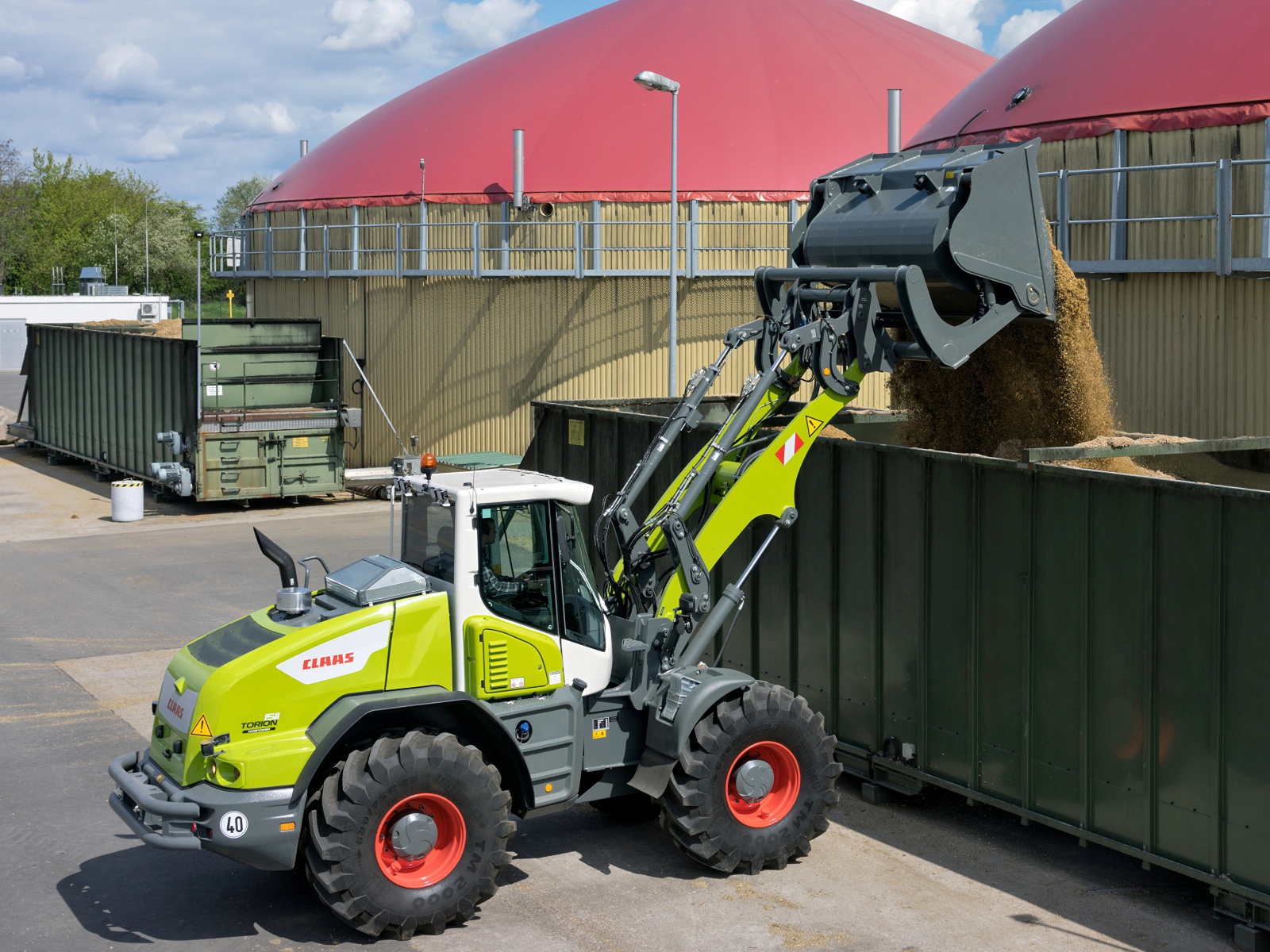Трактор с ковшом высыпает песок в контейнеры 