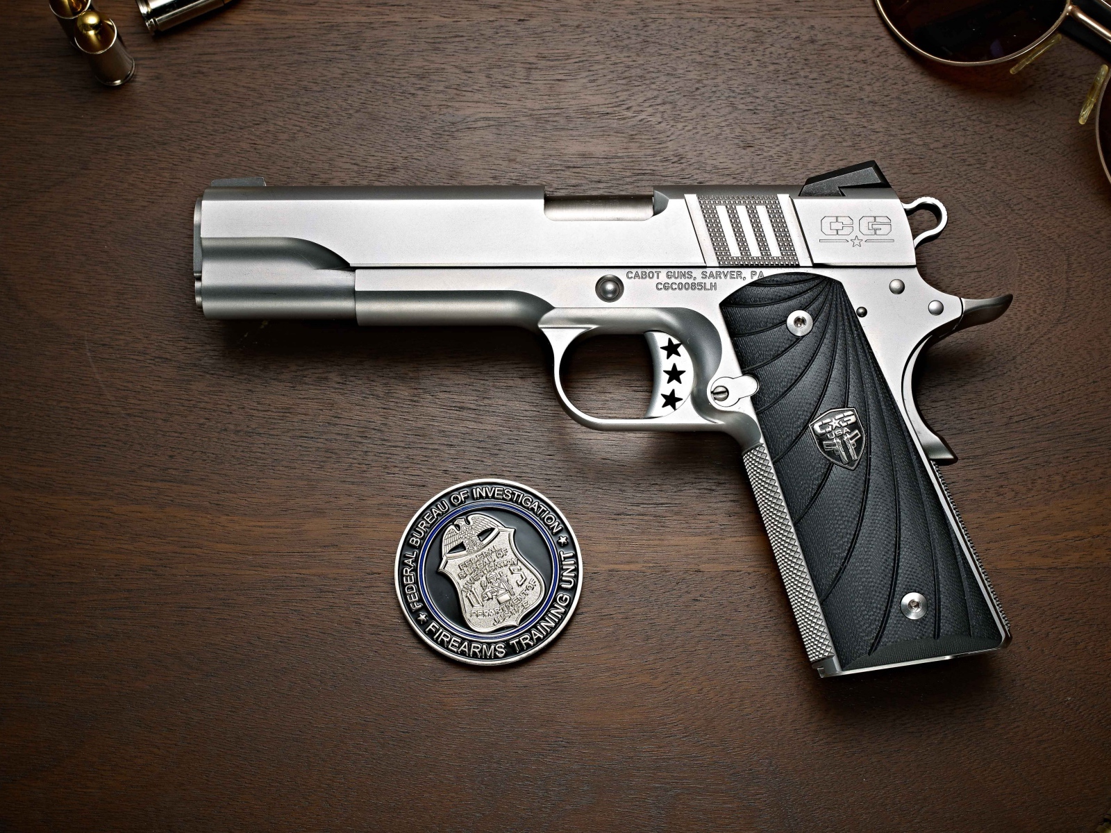 Gun Cabot 1911 lies on a table with glasses and a badge.