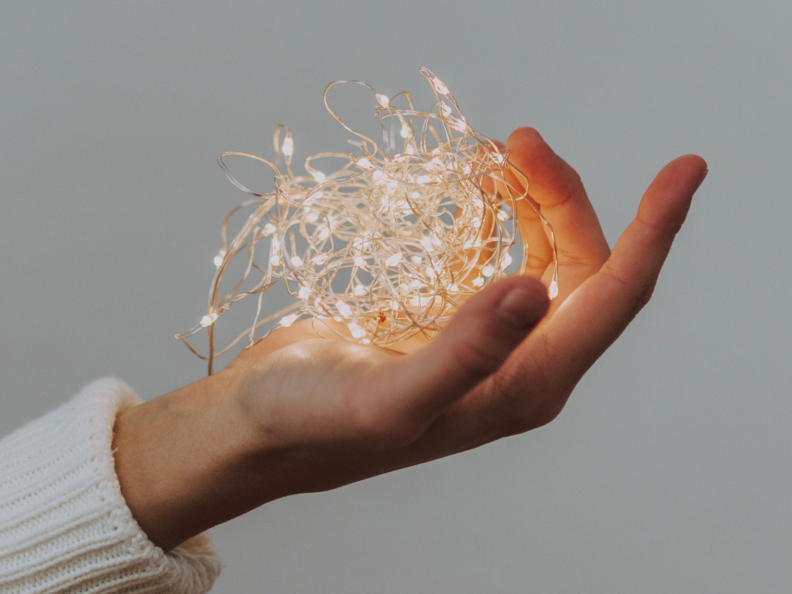 Включенная гирлянда в руке на сером фоне