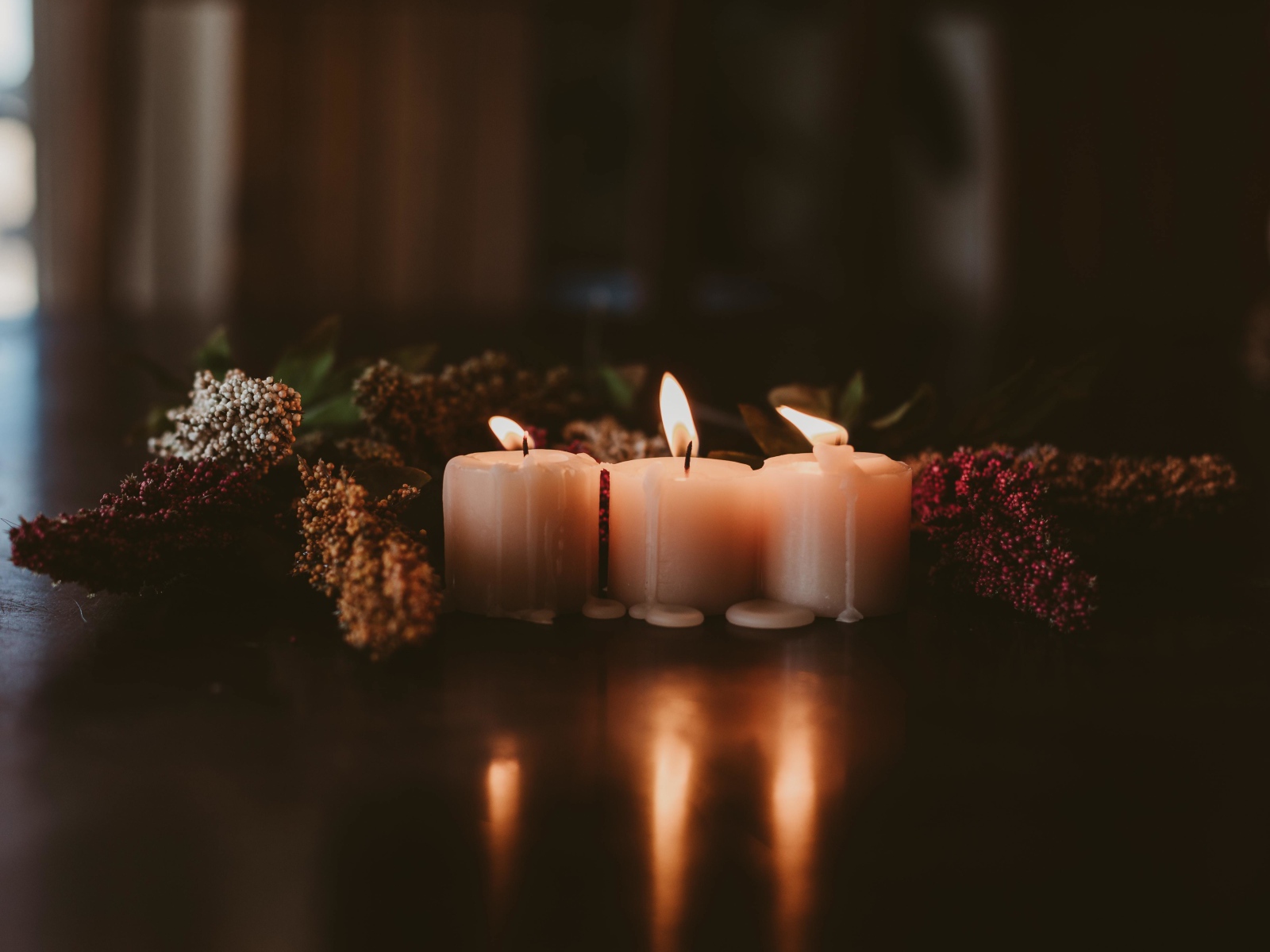Зажженные свечи с цветами на полу