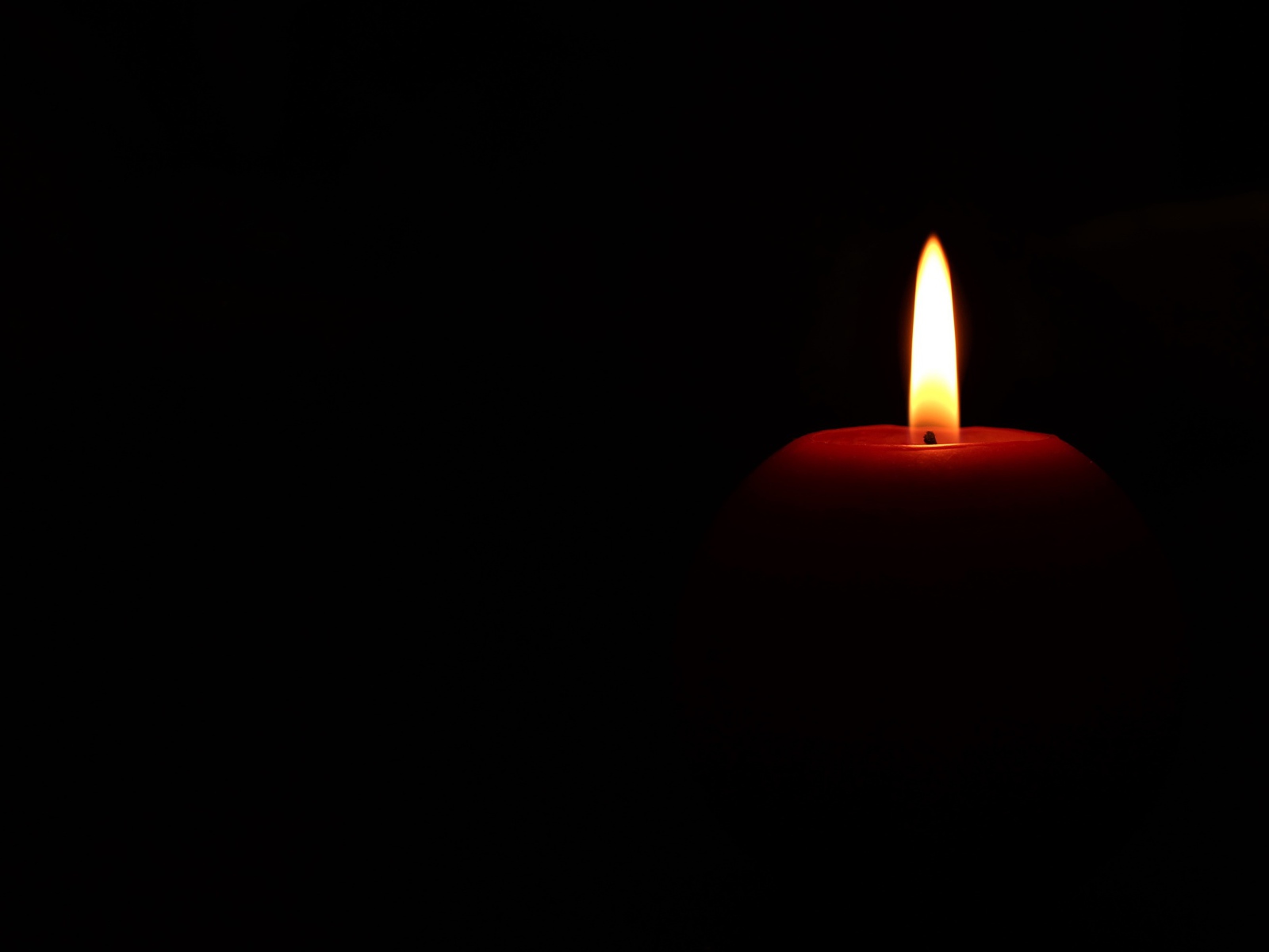 Lighted red candle on black background