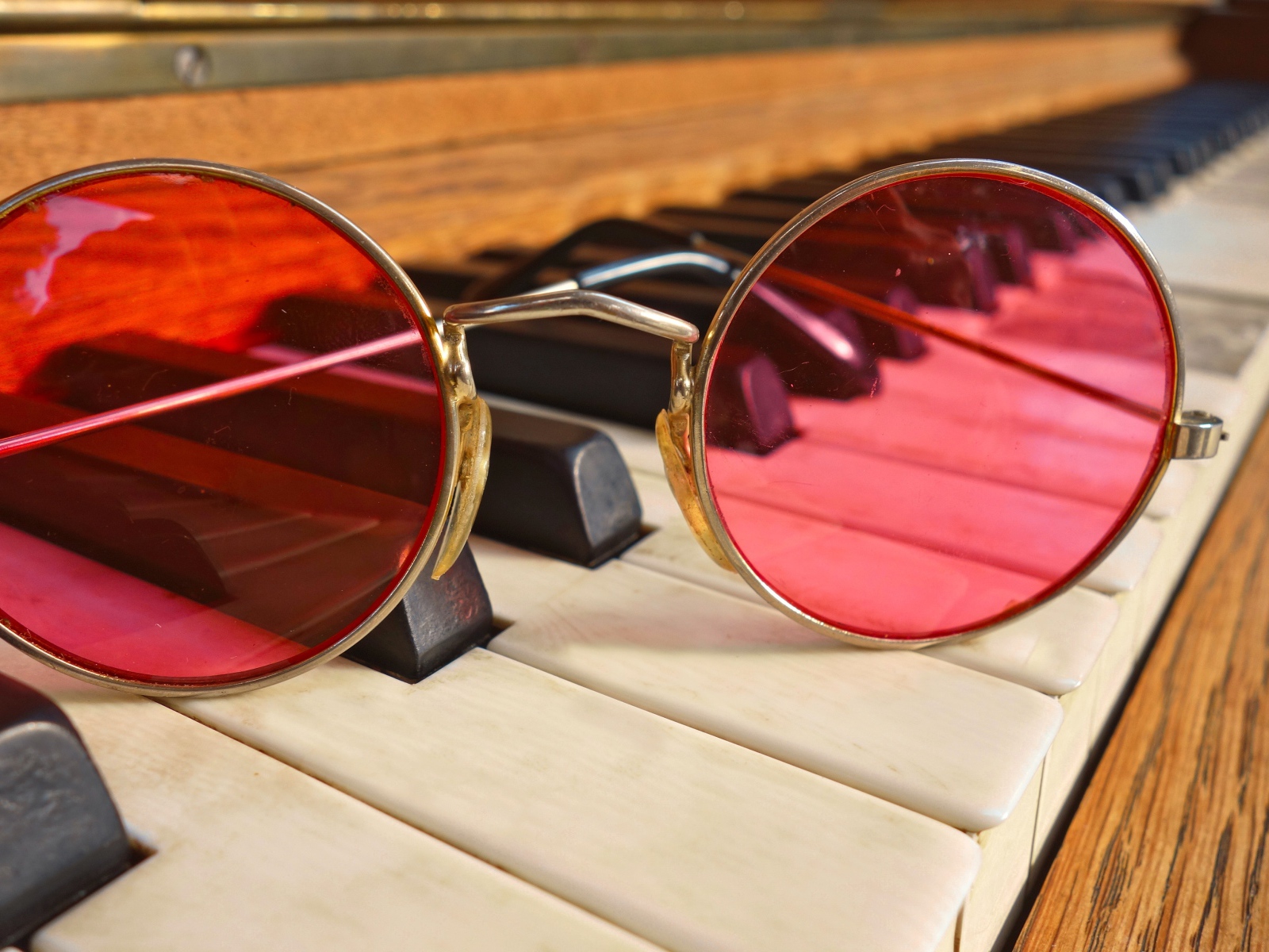 Розовые очки лежат на клавишах рояля