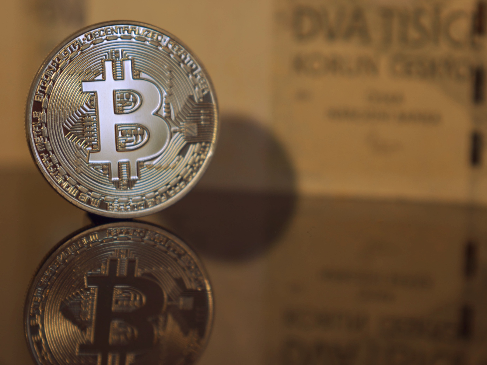 Монета биткоин отражается в зеркальной поверхности 