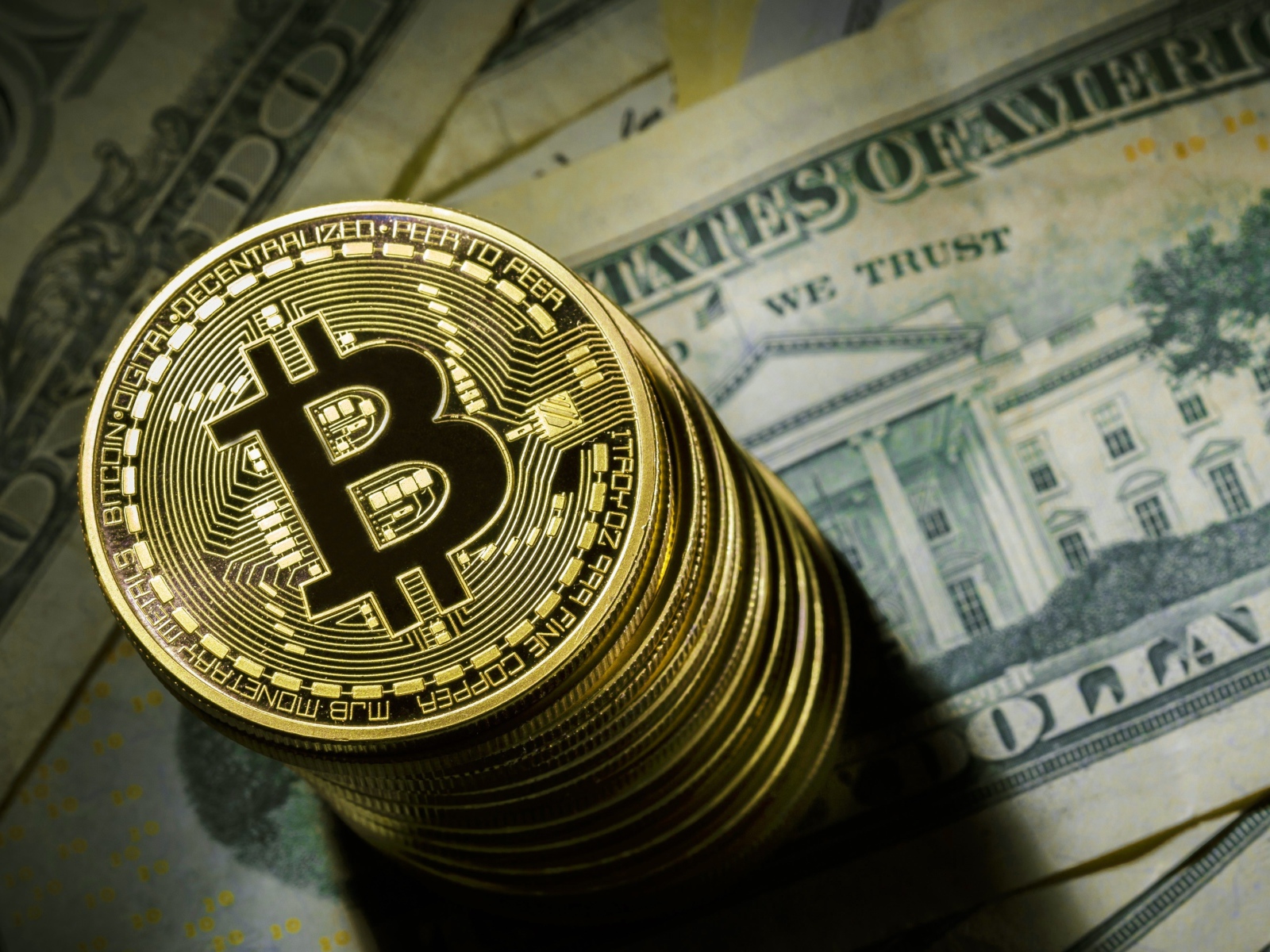 Золотые монеты биткоин лежат на долларах