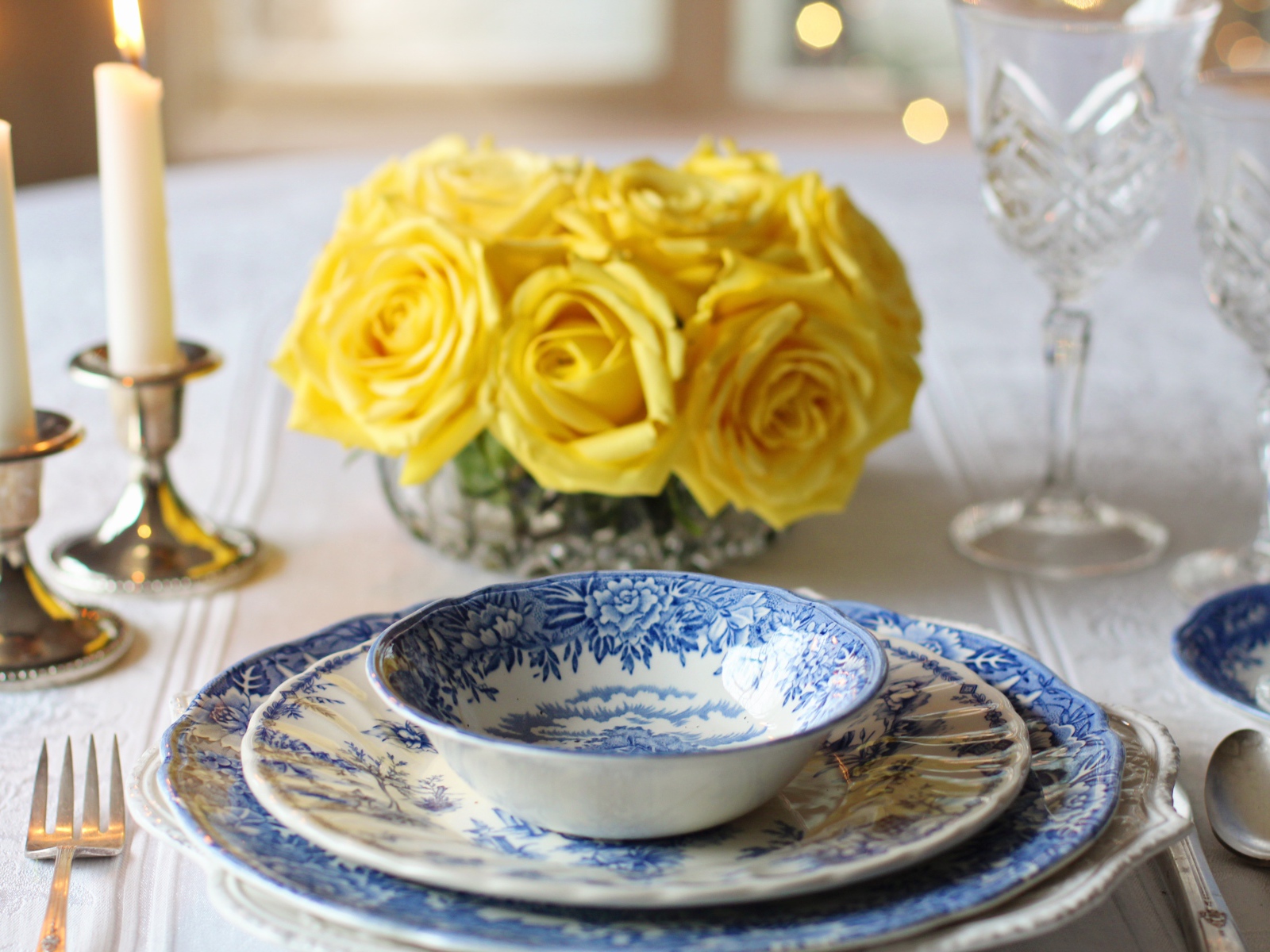 Красивая посуда на столе с букетом роз и свечами