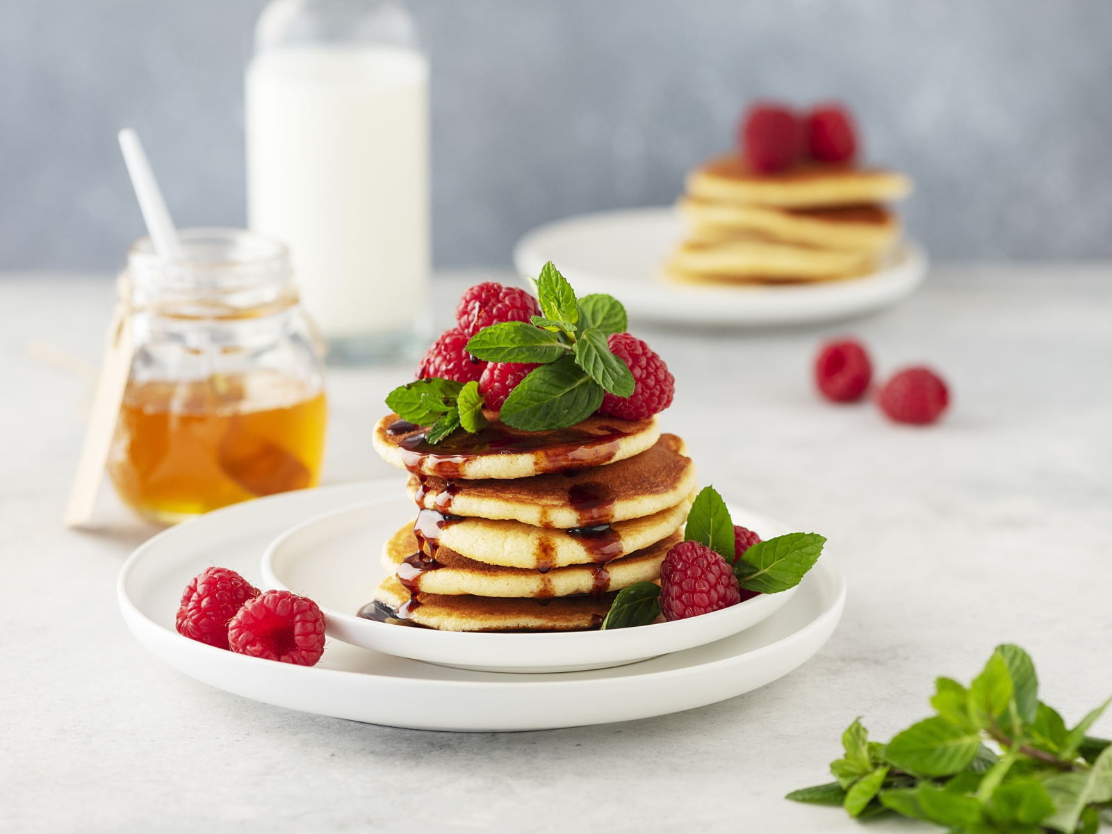 Румяные оладьи на тарелке с малиной и мятой 