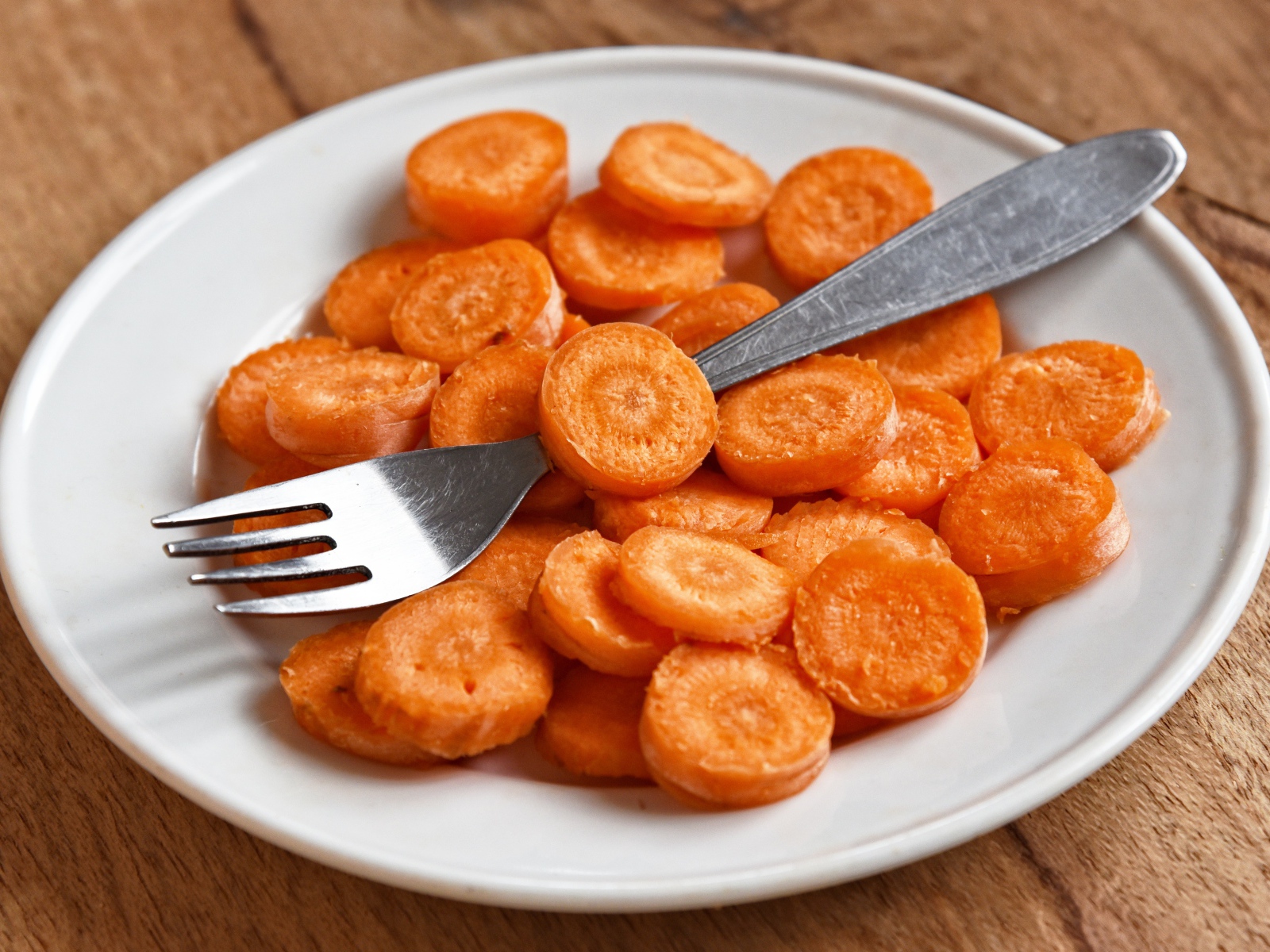 Carrot slices on a white plate with a fork