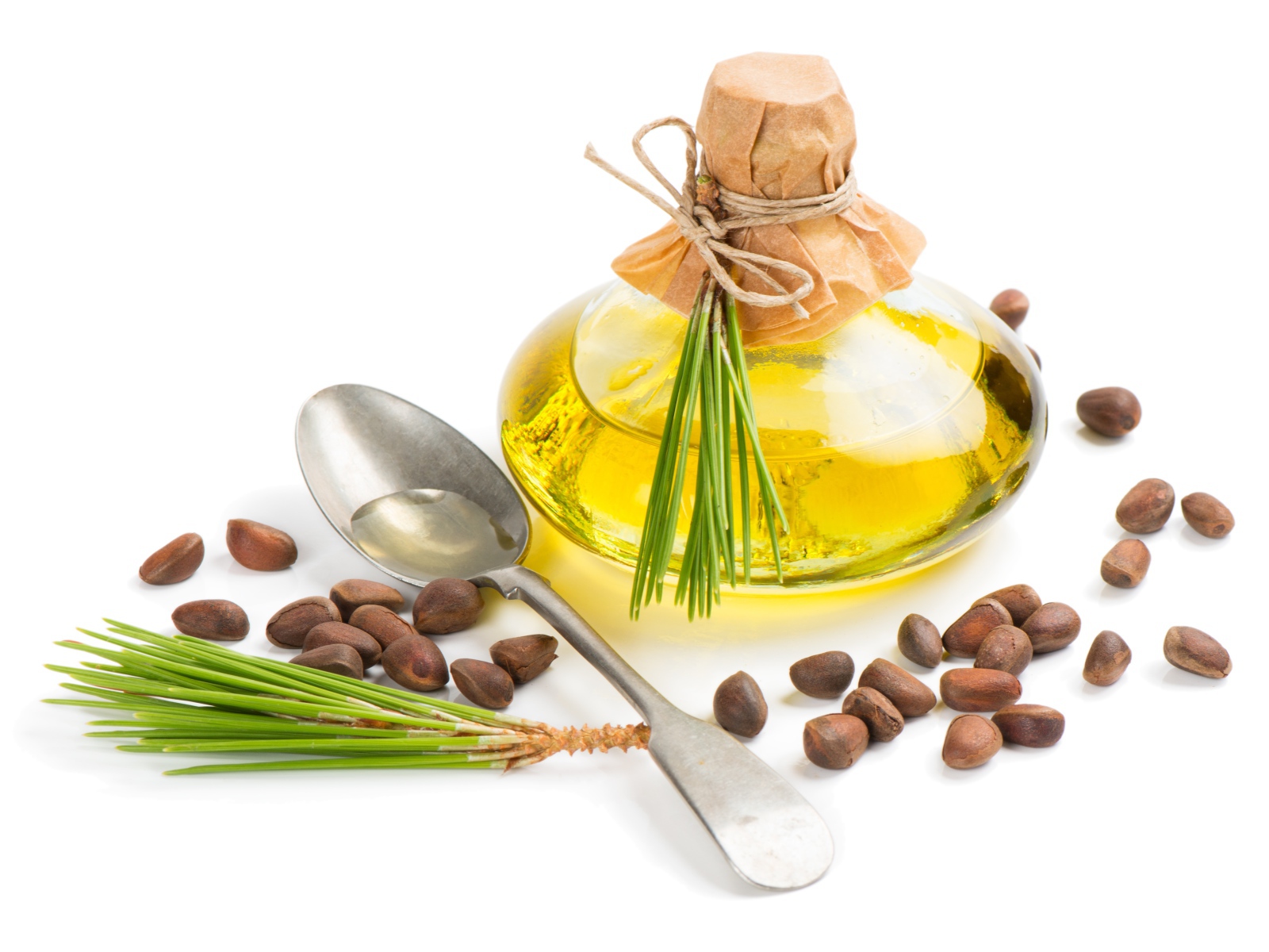 Кедровое масло на белом фоне с орехами и ложкой