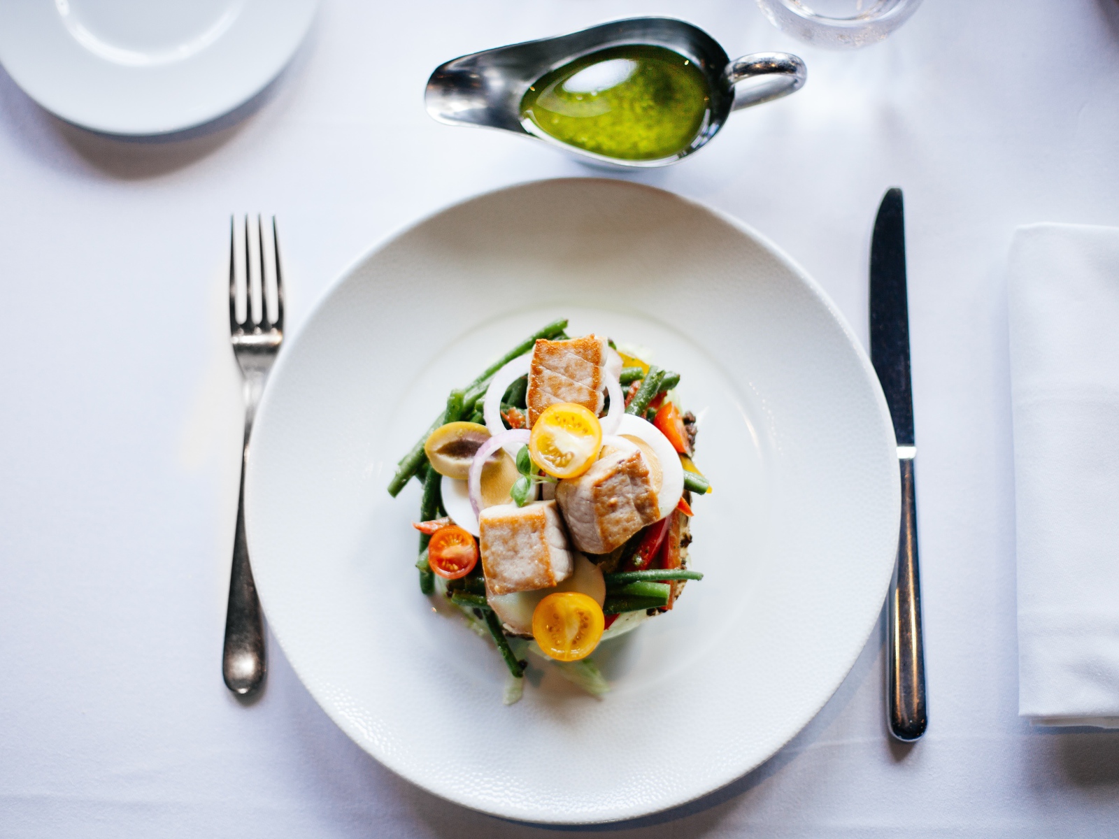 Салат из куриного филе с овощами на белой тарелке