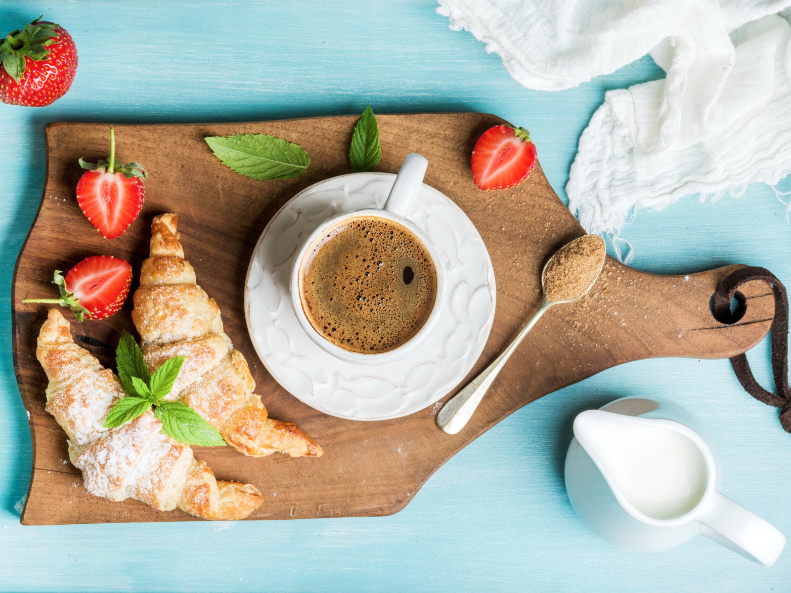 Чашка кофе на доске с клубникой и круассанами