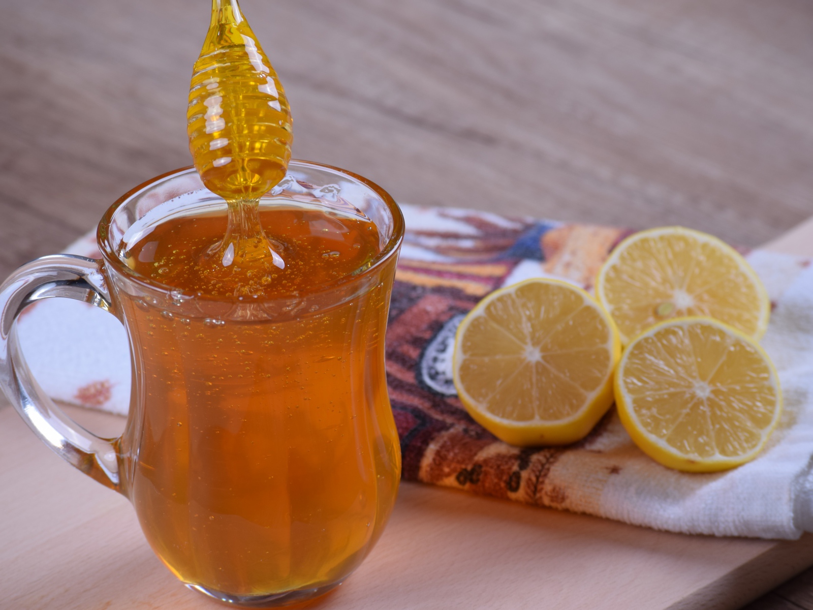Glass mug with honey on the table with lemon