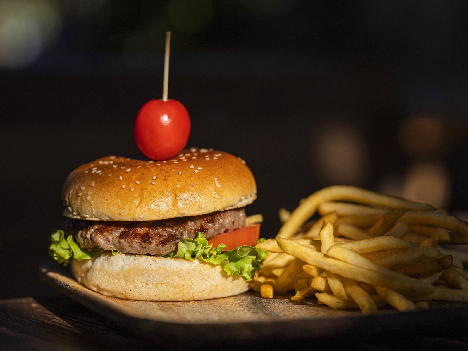 Гамбургер с помидором на доске с картофелем фри 