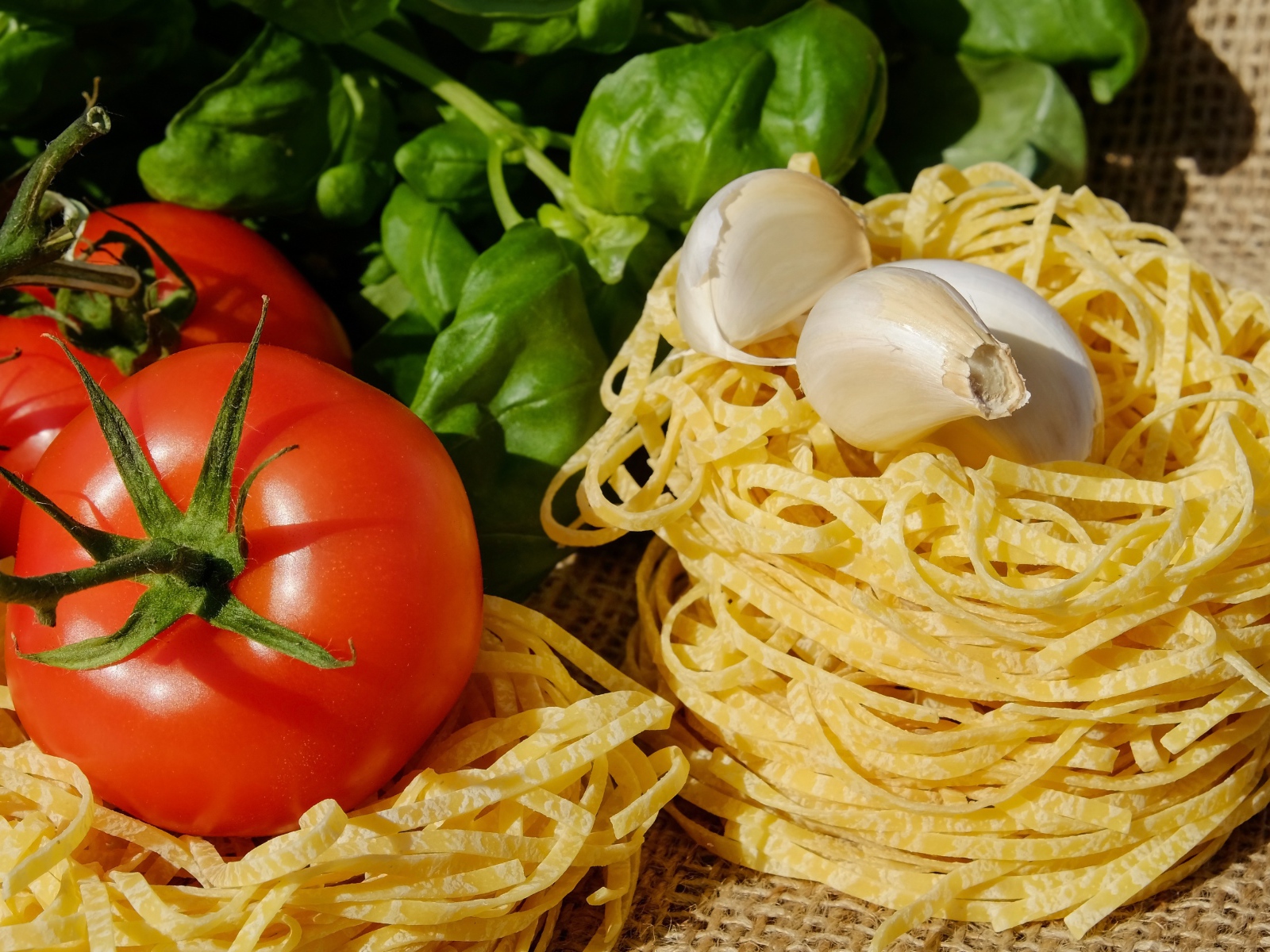 Домашняя лапша на столе с помидорами и базиликом