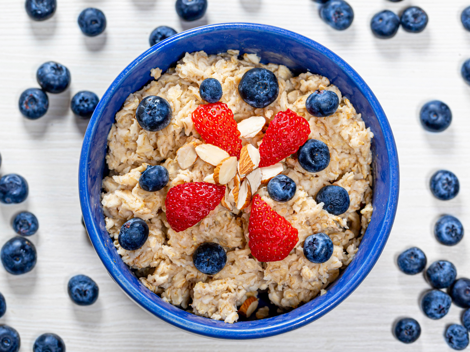 Овсяная каша в тарелке с ягодами черники и клубники 