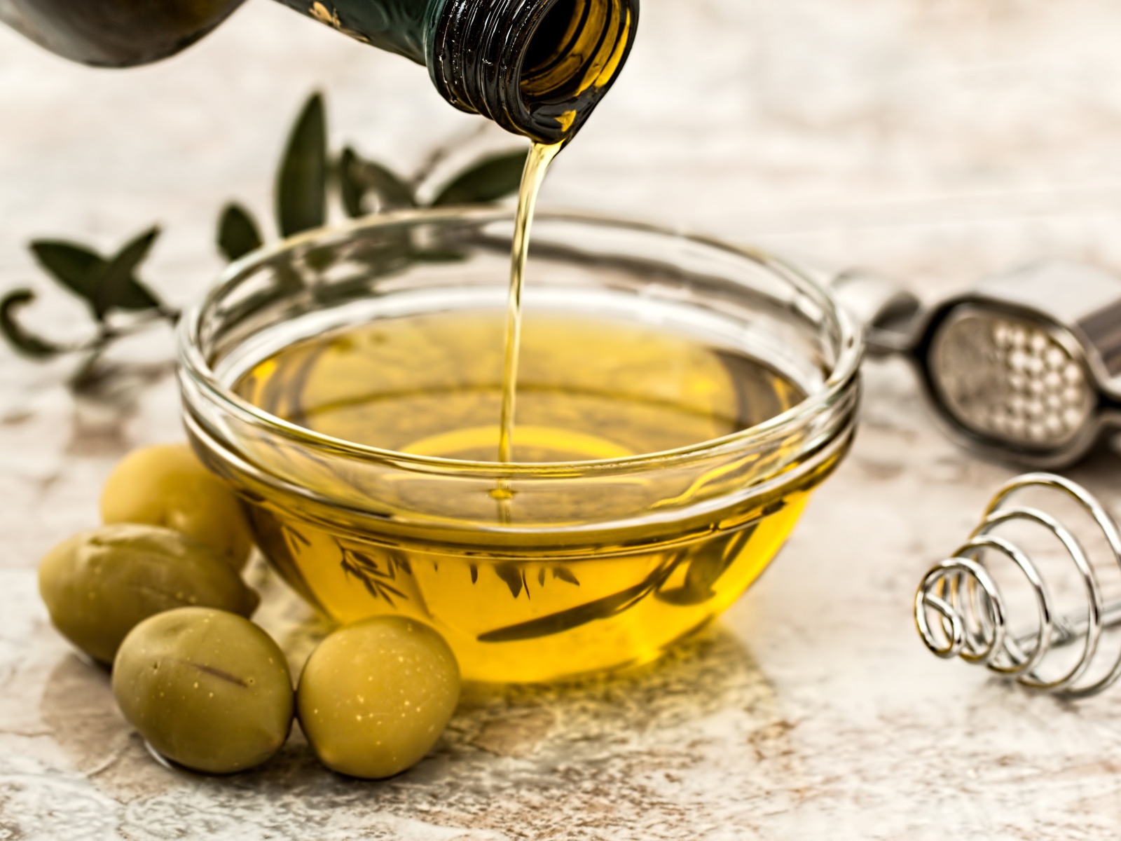 Оливковое масло в стеклянной тарелке на столе 