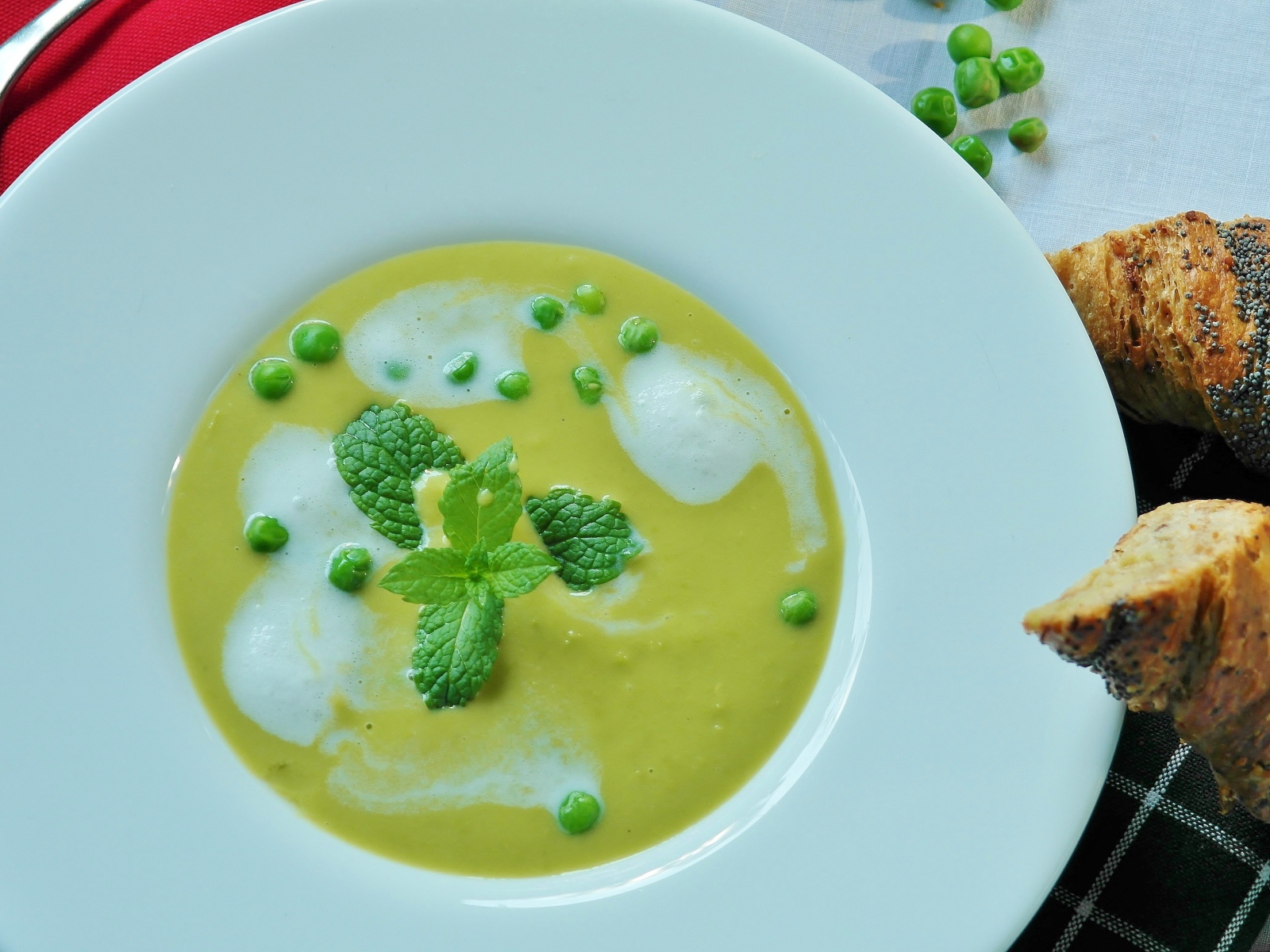 Суп пюре с зеленым горошком в белой тарелке 