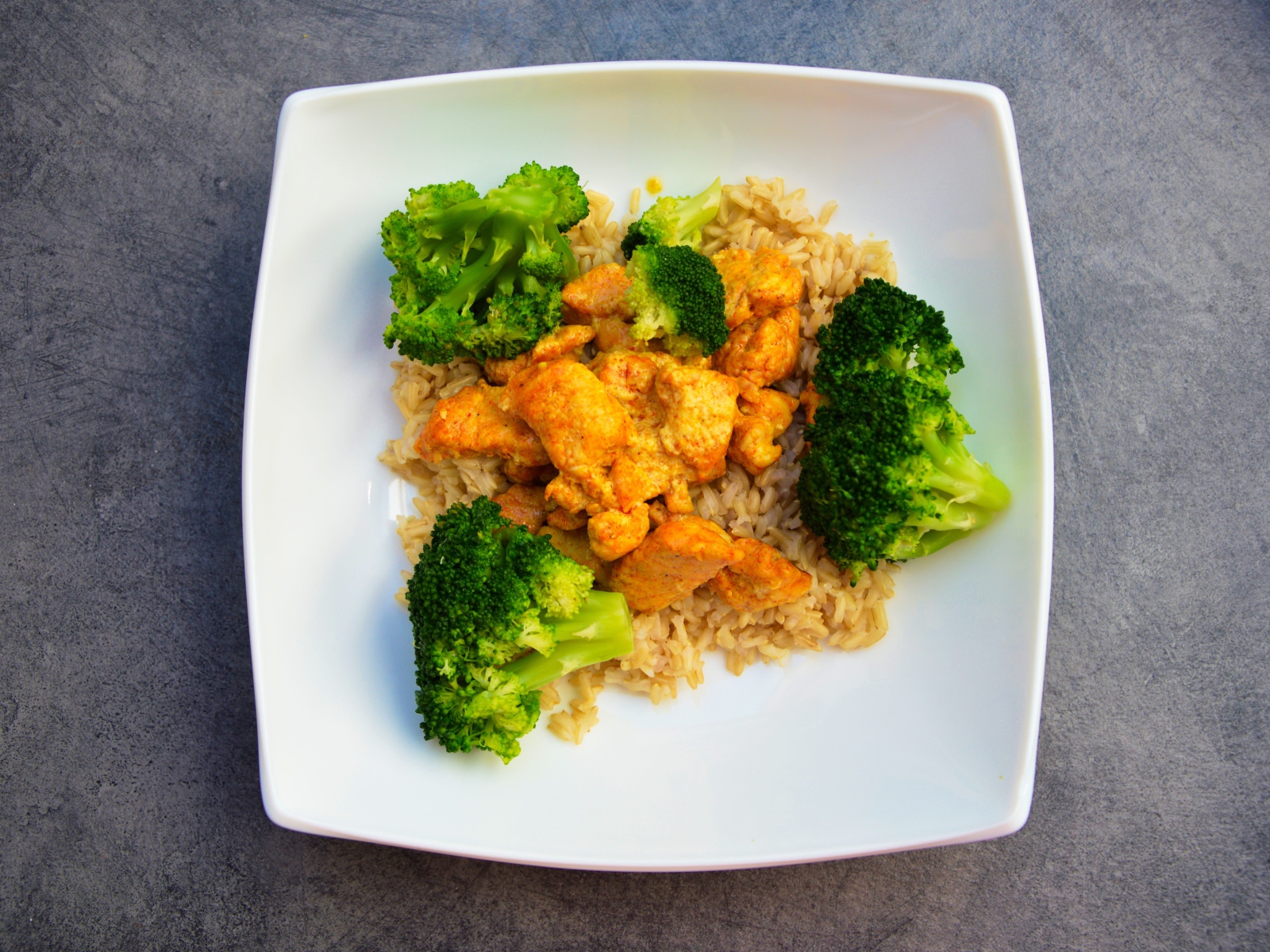 Rice with meat and broccoli in a white plate