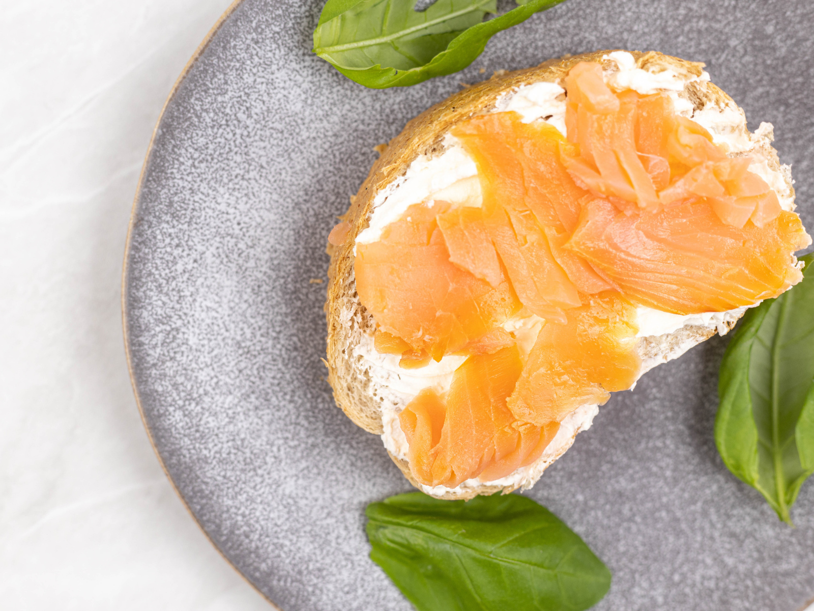 Бутерброд с сыром, красной рыбой и листьями базилика