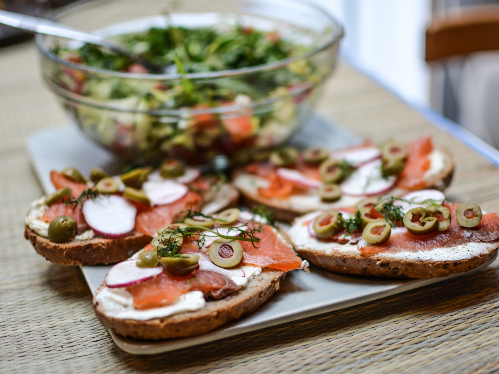 Бутерброды с маслом и красной рыбой на столе с салатом