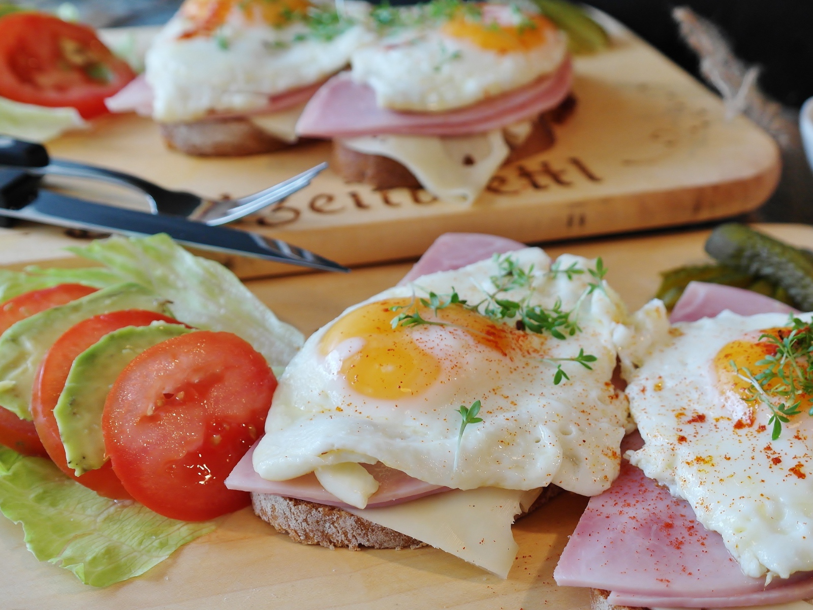 Бутерброды с яичницей и беконом на столе с овощами