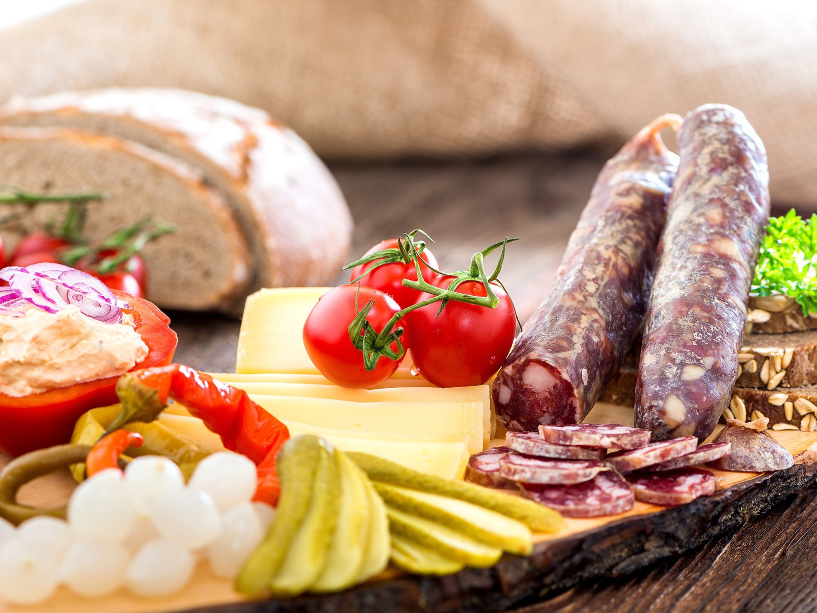 Колбаса на столе с огурцами, помидорами и перцем