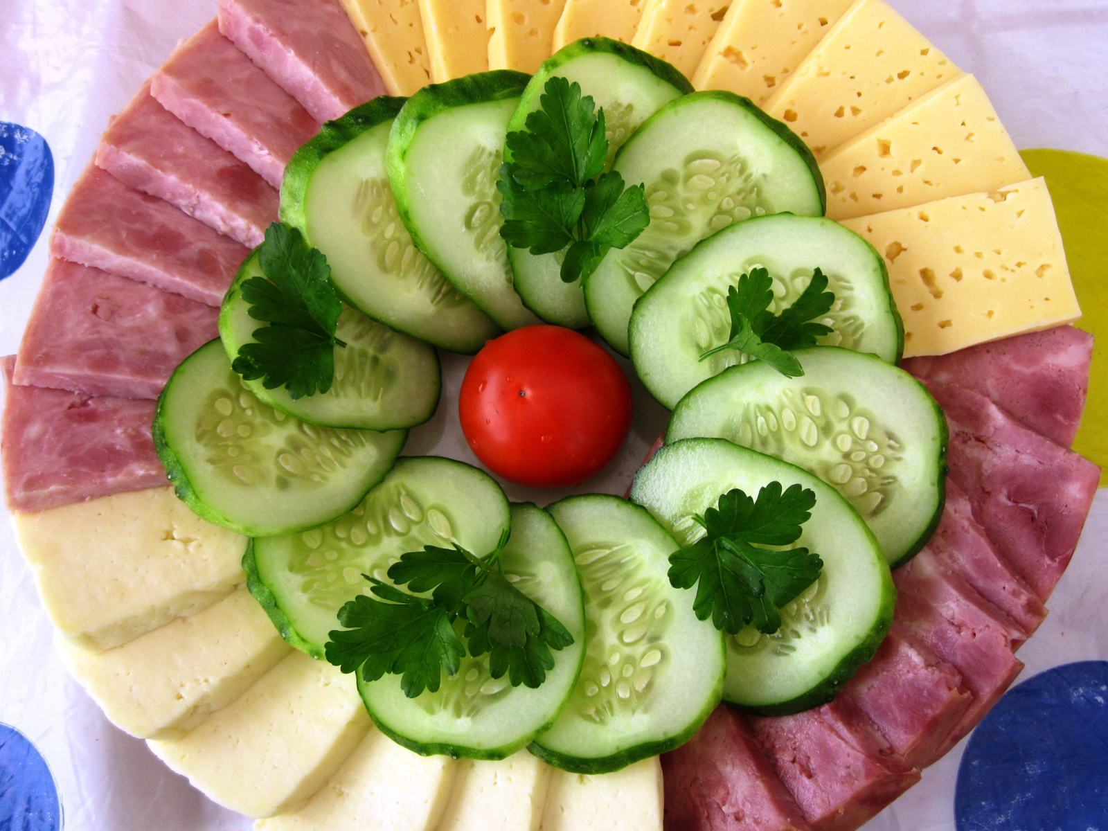 Sliced cheese, cucumbers and ham on a plate