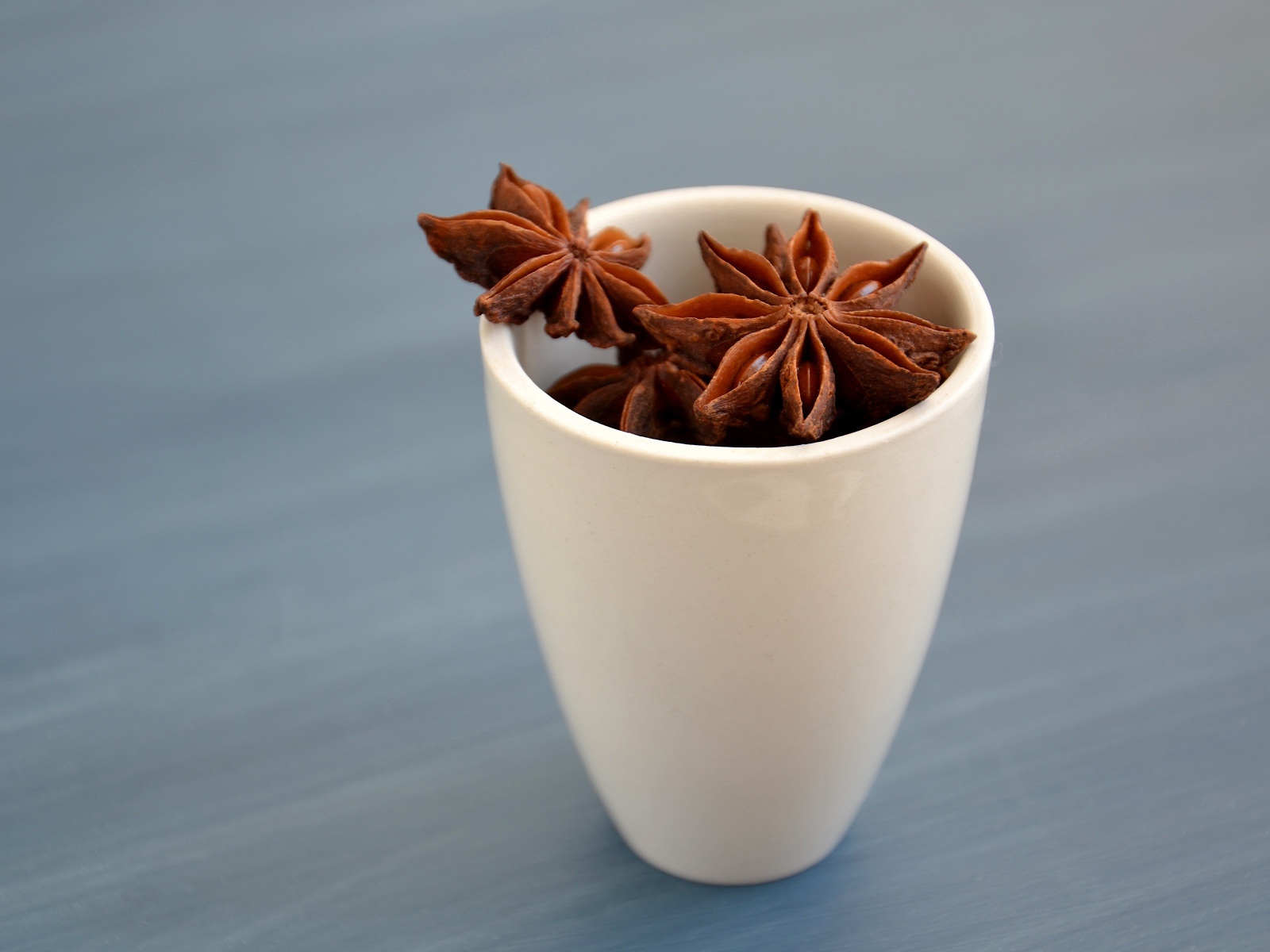 Звездочки бадьяна в белой чашке на столе 