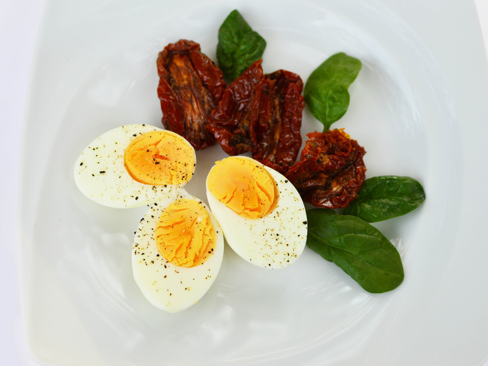 Вяленые помидоры на тарелке с базиликом и вареными яйцами