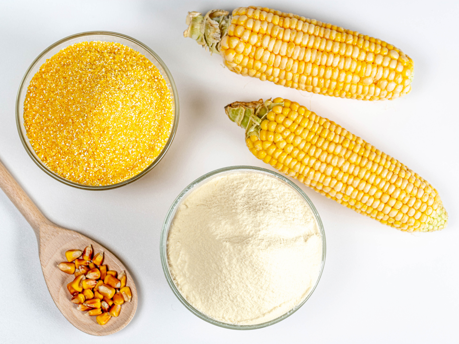 Два початка кукурузы на белом фоне с крупой и мукой 