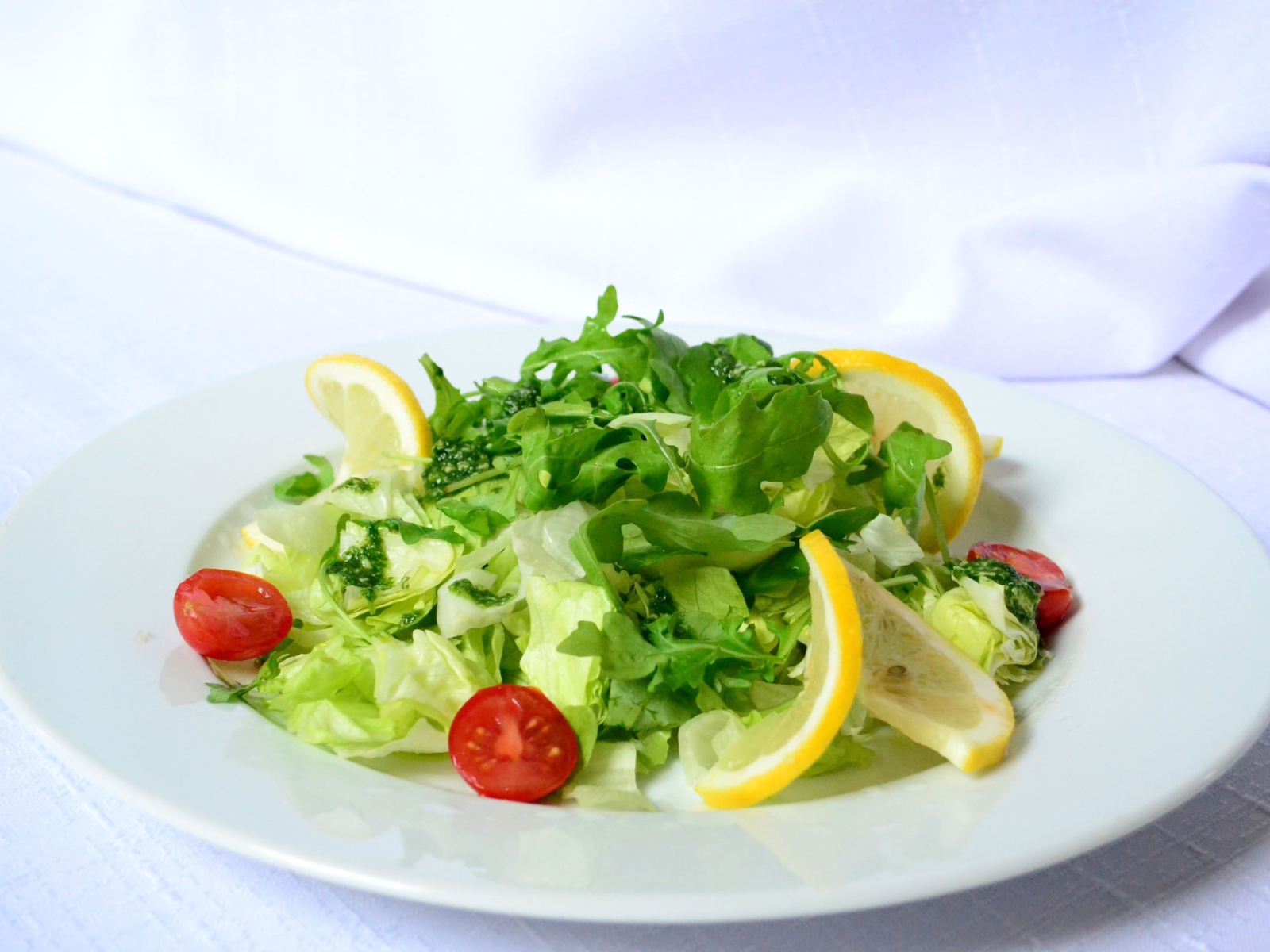 Белая тарелка со свежим зеленым салатом 