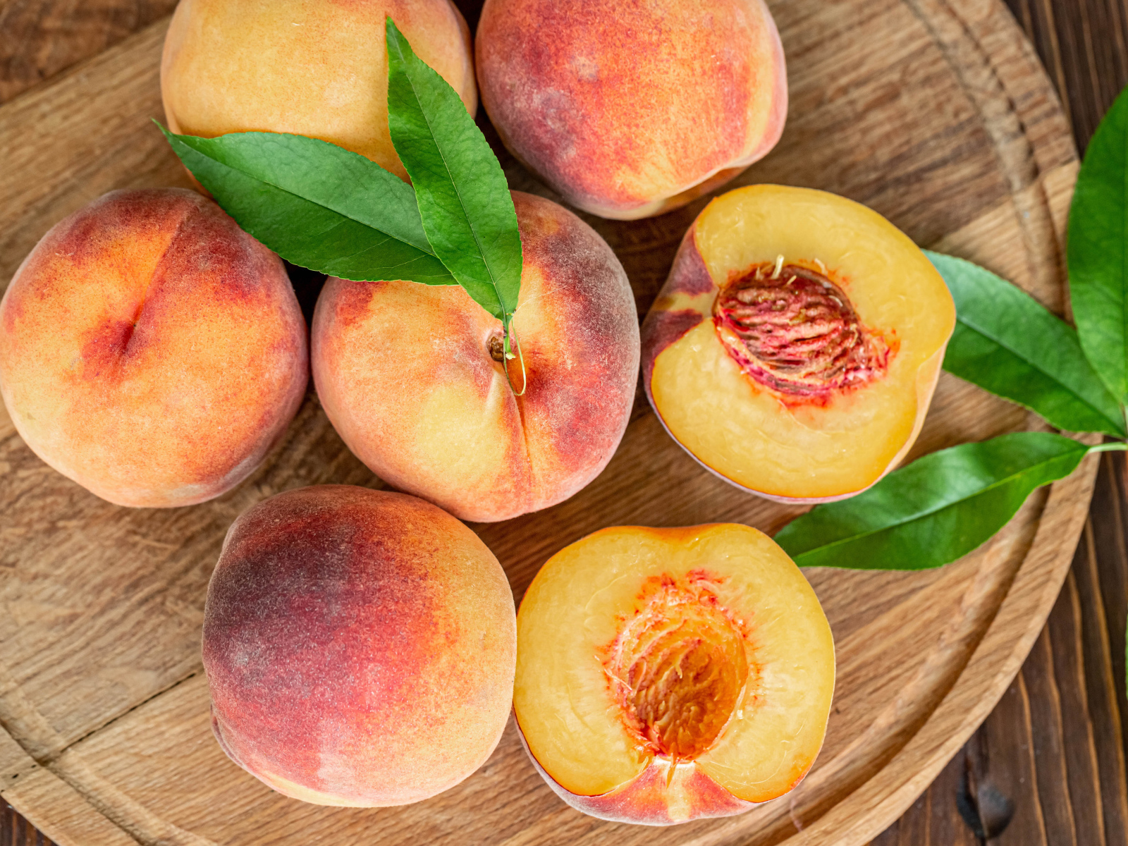 Аппетитные свежие персики на деревянной доске