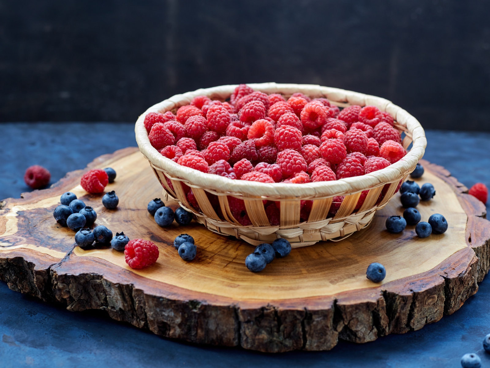 Корзинка с малиной на столе с ягодами черники