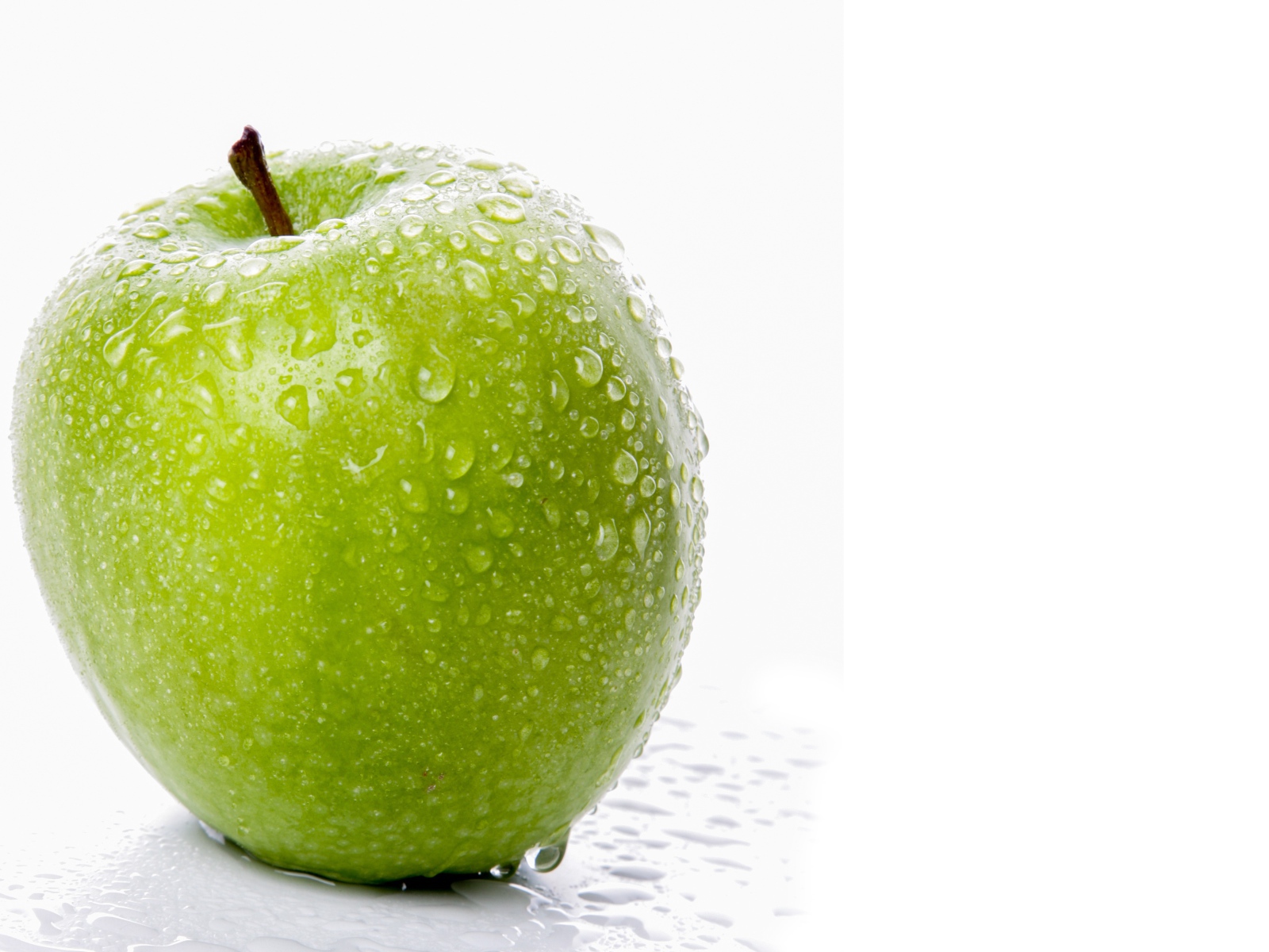 Зеленое яблоко в воде на белом фоне
