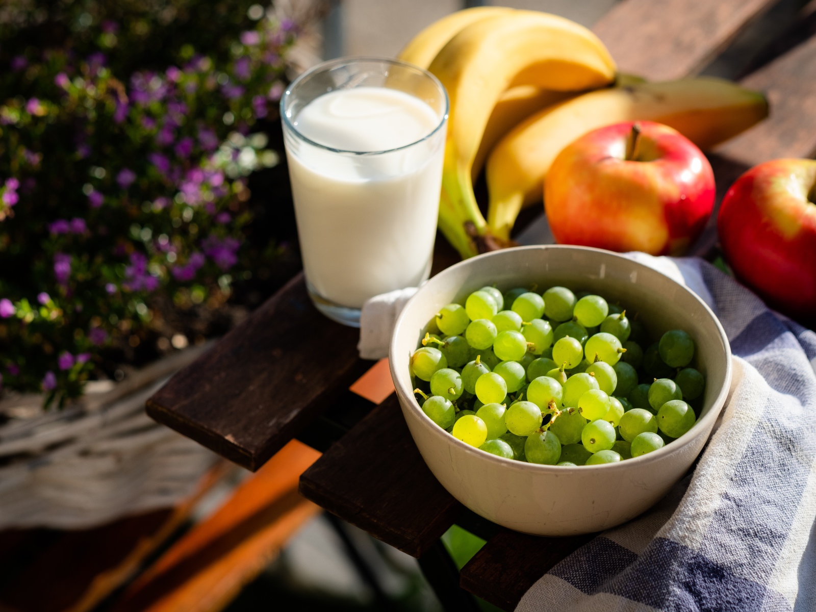 Зеленый виноград на столе с бананами, яблоками и молоком