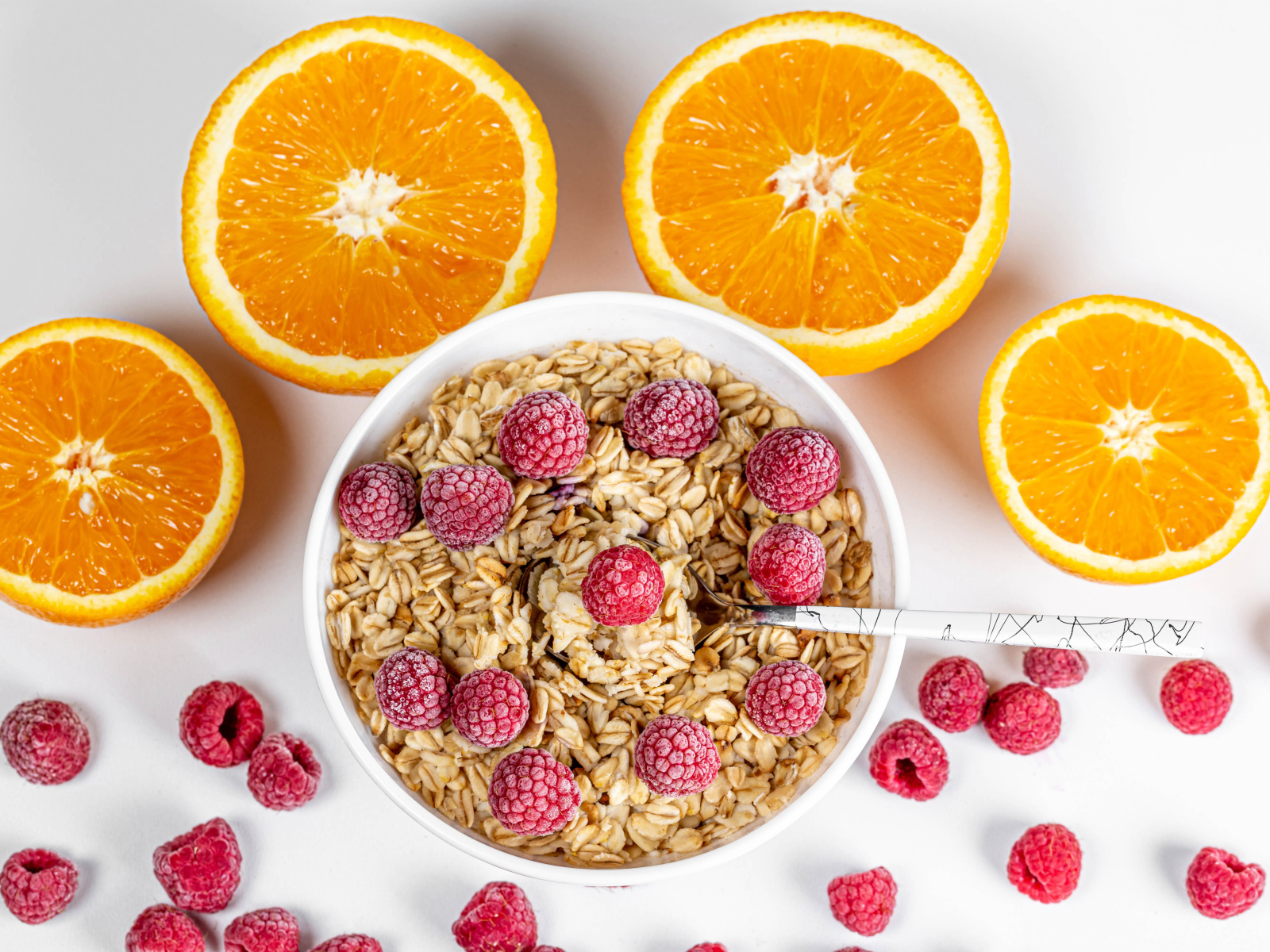 Овсяные хлопья с малиной на белом фоне с апельсинами