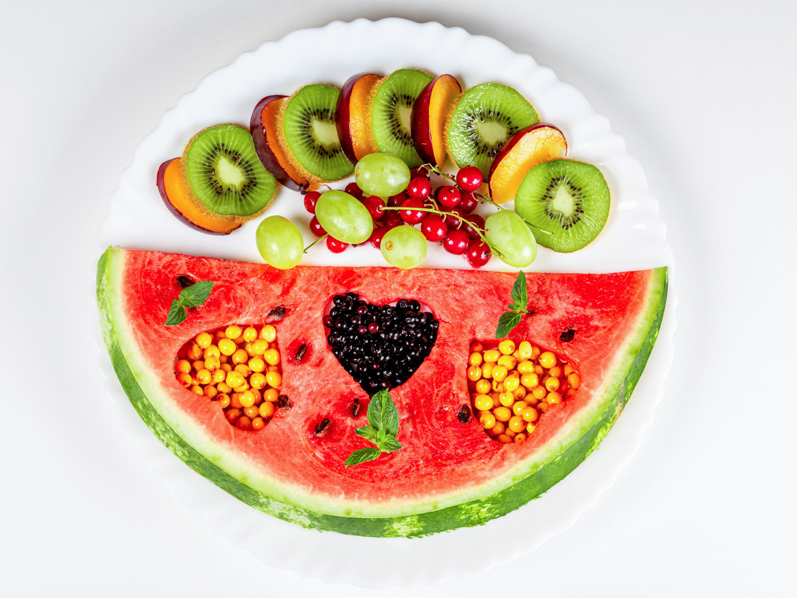 Кусок арбуза на тарелке с киви и ягодами 