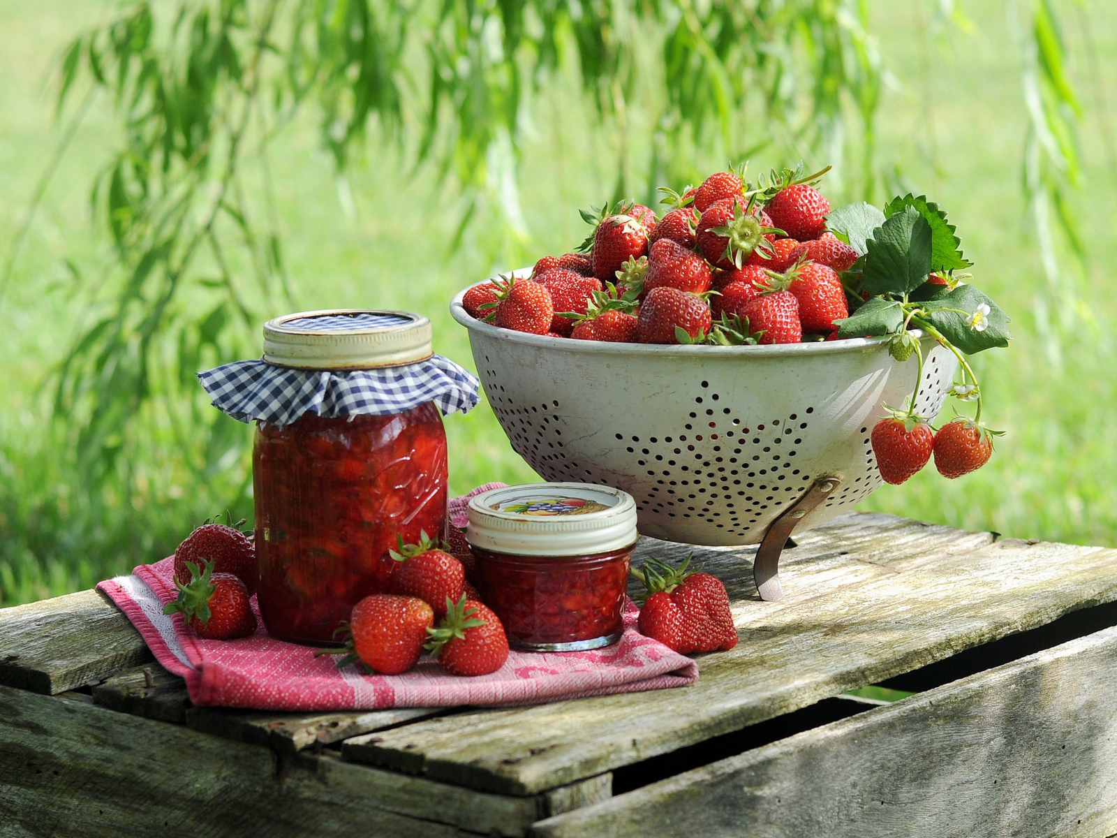 Ripe red strawberries with jam stand on a box