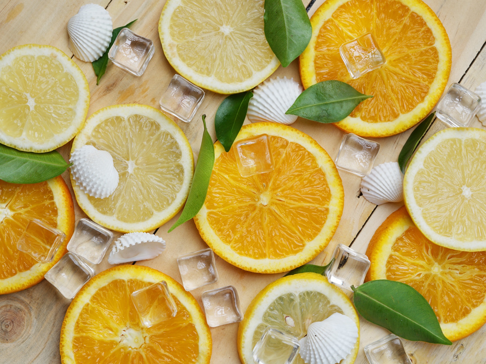 Кусочки апельсина и лимона на столе с кубиками льда и ракушками