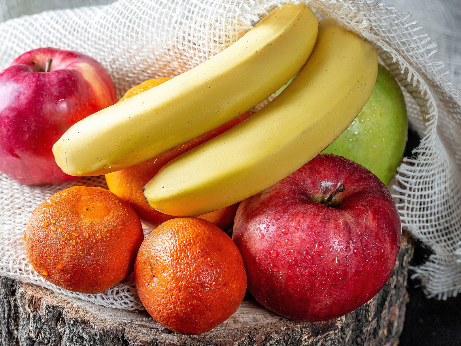 Мокрые бананы, яблоки и мандарины на столе 
