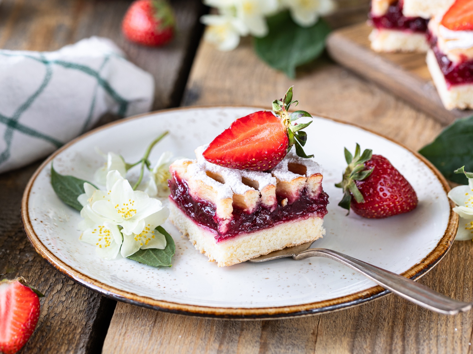 Кусок пирога на тарелке с клубникой и цветами жасмина