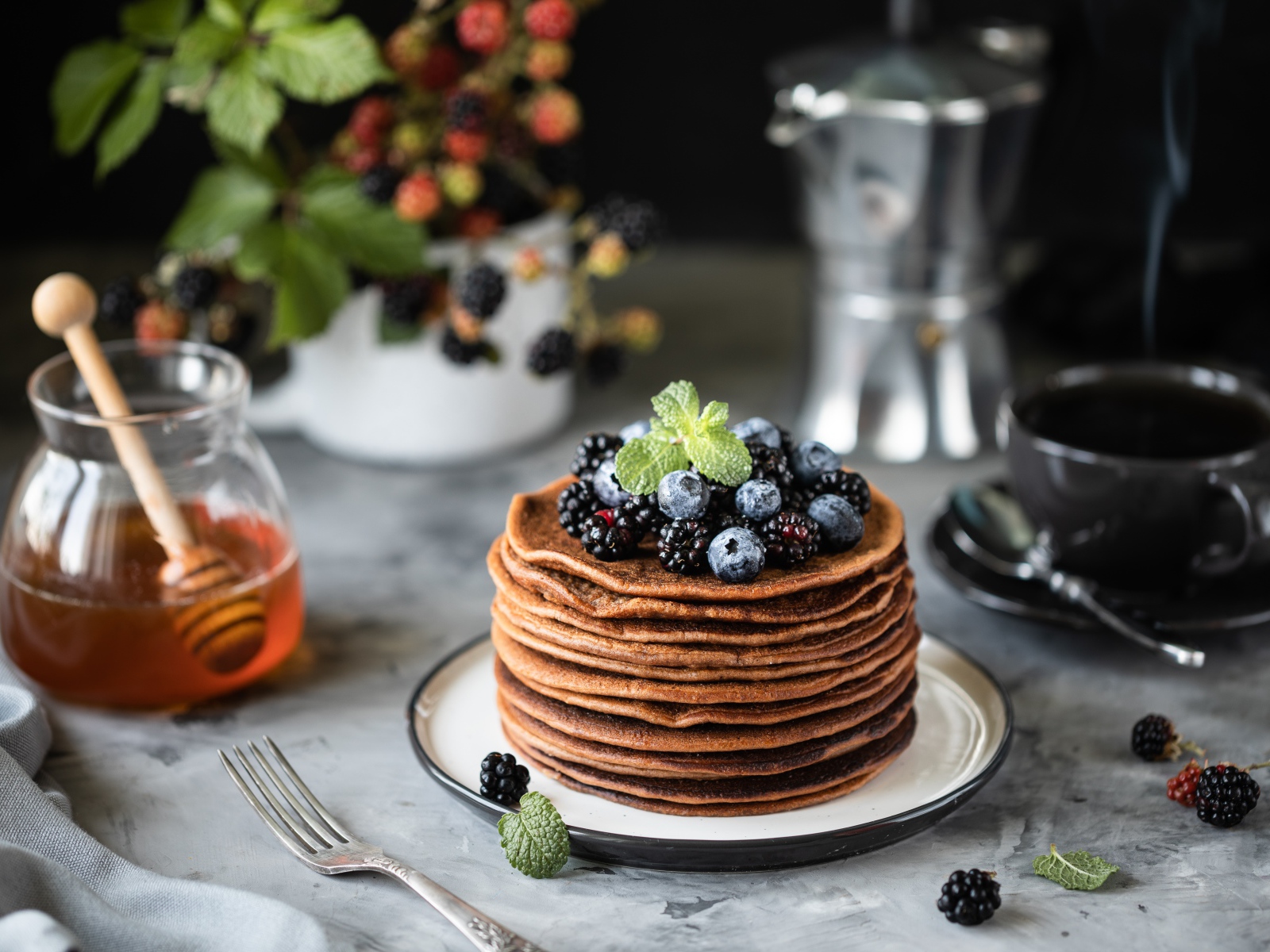 Гречневые блинчики с ягодами на столе с медом